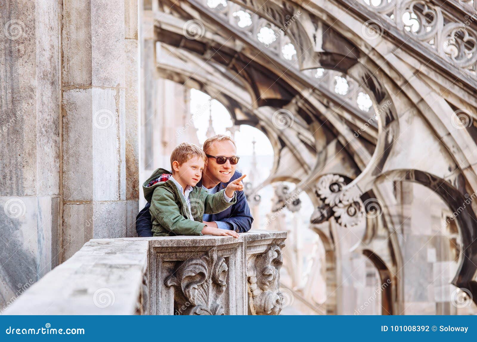 father with son tourists are on the roof of milan cathedral