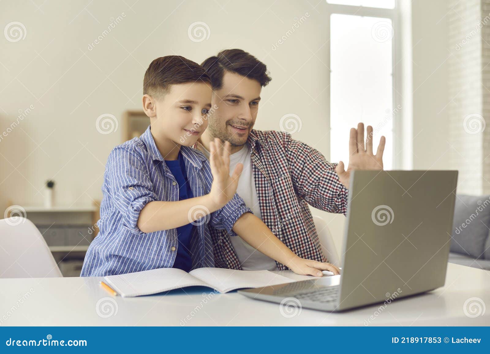 father and son wave greeting gesture talk to laptop web camera during video call