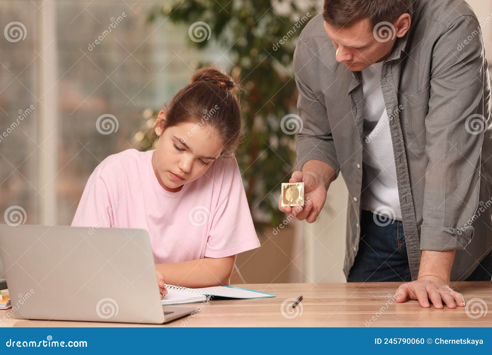 Father Talking with His Teenage Daughter about Contraception while she Using Laptop at Home
