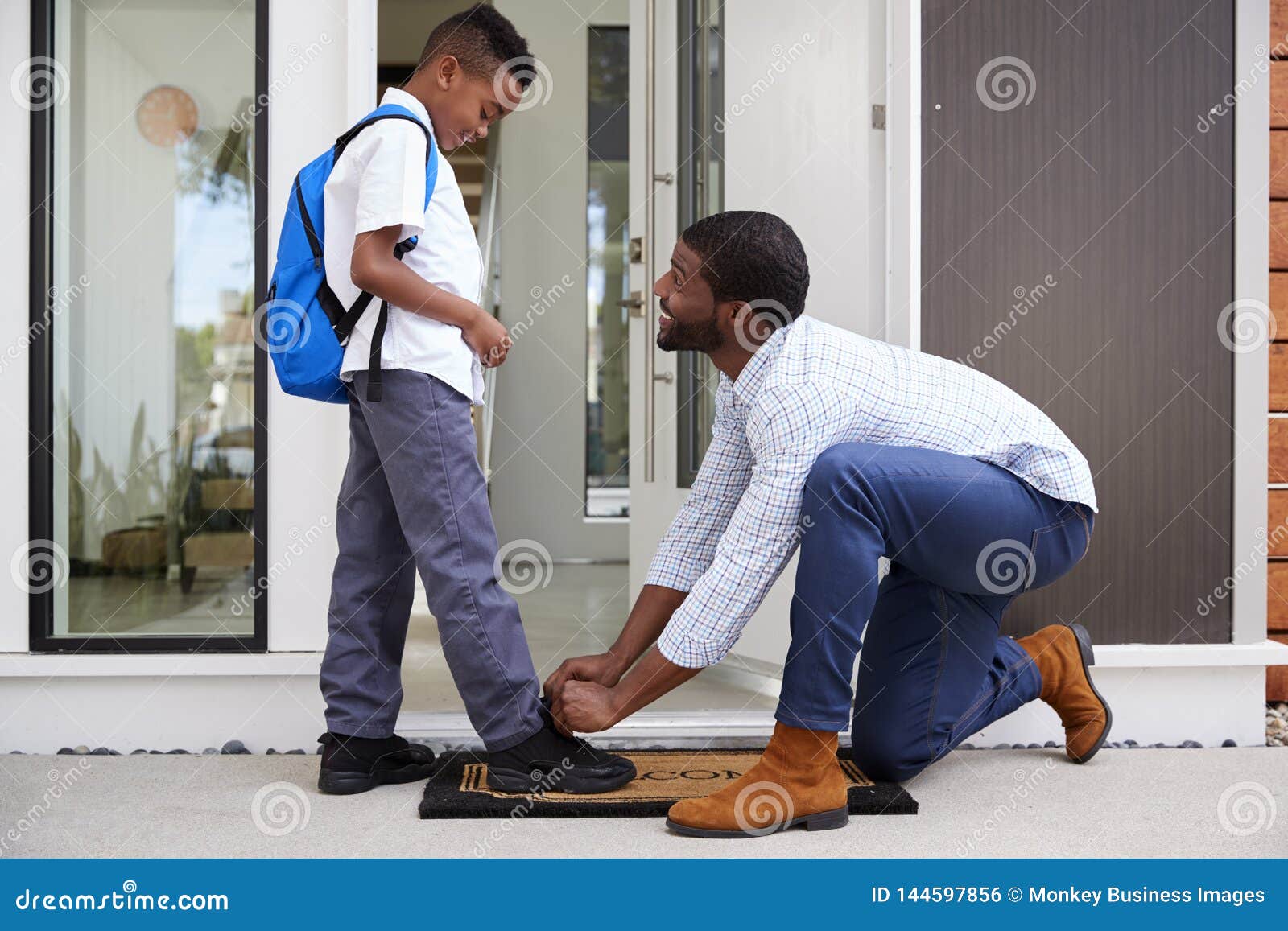 father tying sons shoelaces as he leaves for school
