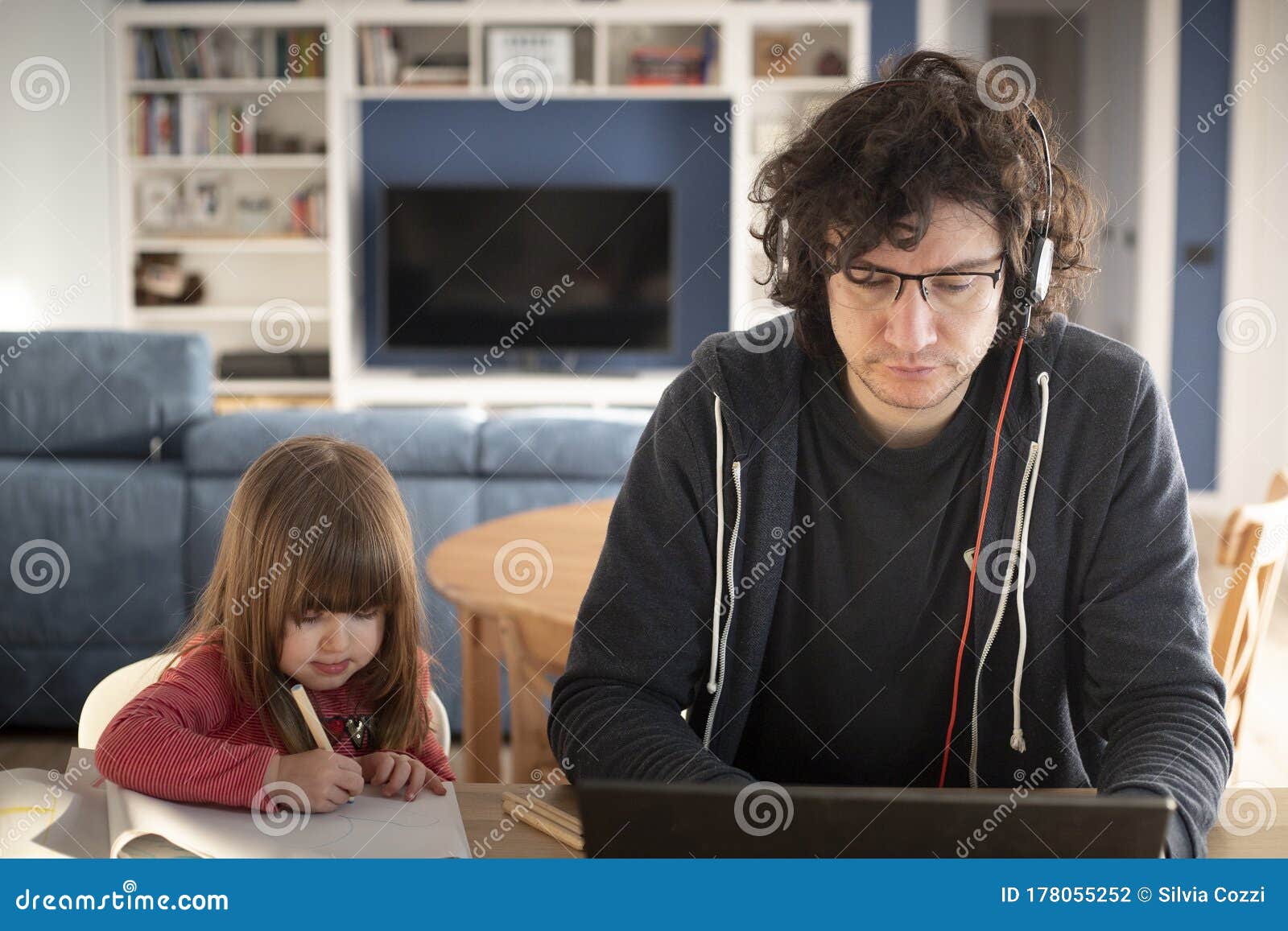 father working from home with little daughter during covid-19 lockdown