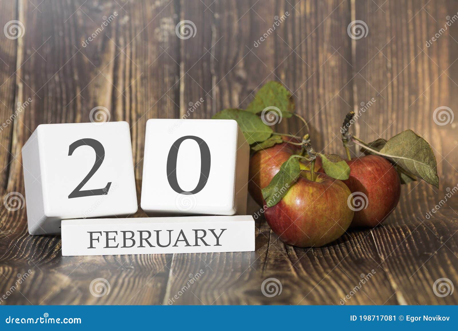 february 20. day 20 of month. calendar cube on wooden background with red apples, concept of business and an important event.