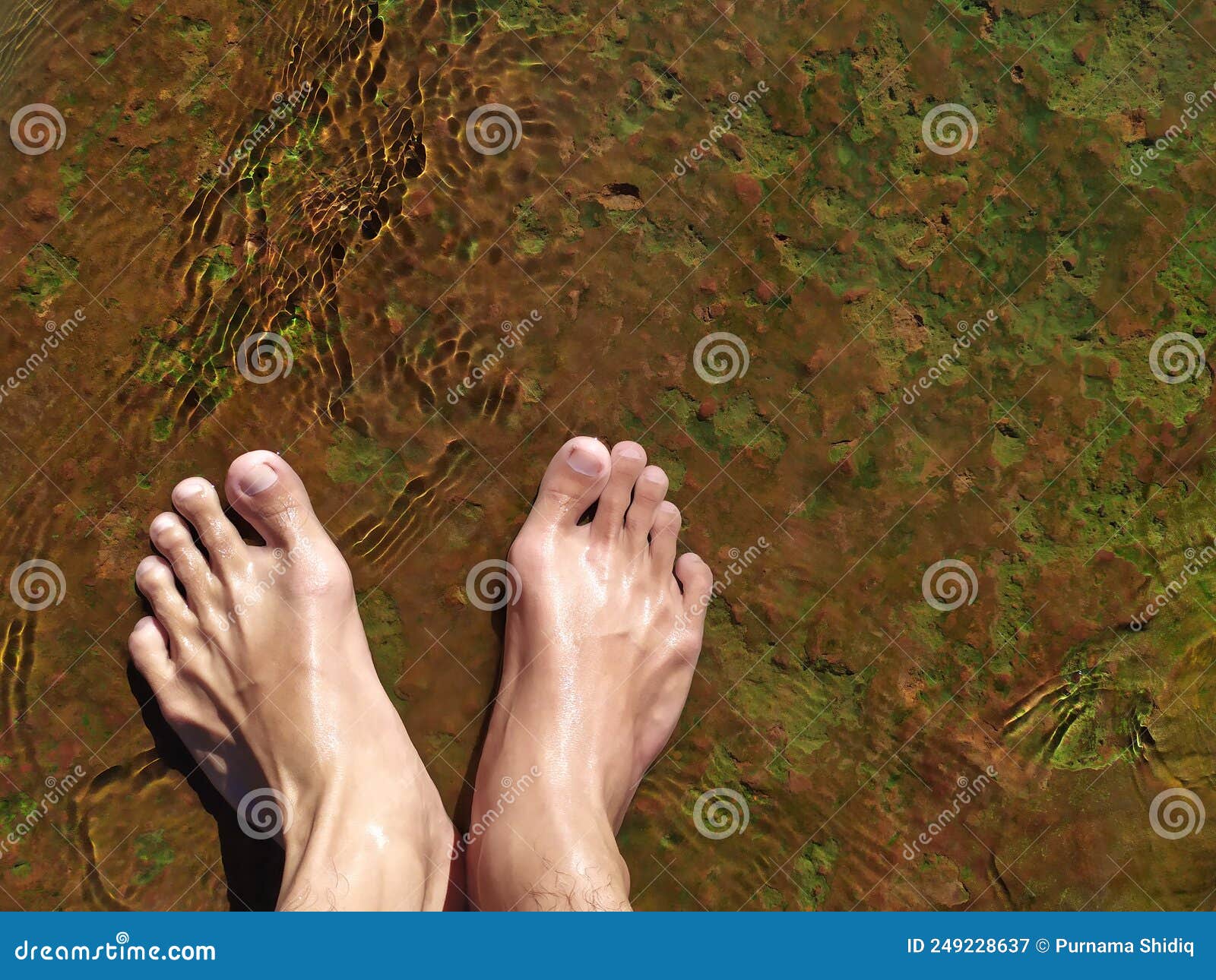 The Feet of a Man Standing on a Rock Running Hot Water. Stock Image