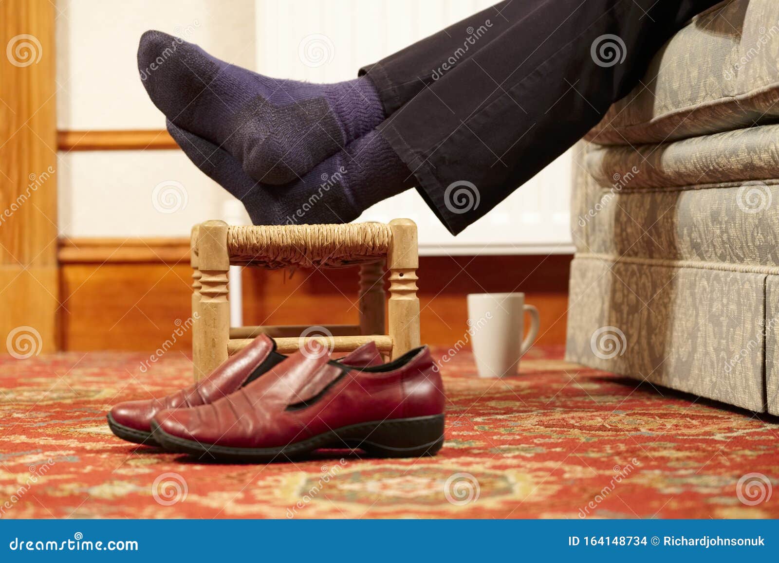 Feet Resting On Foot Stool No Shoes With Cup Of Hot Drink For