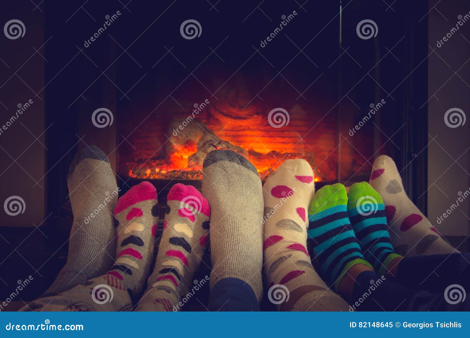 feet in socks of all the family warming by cozy fire