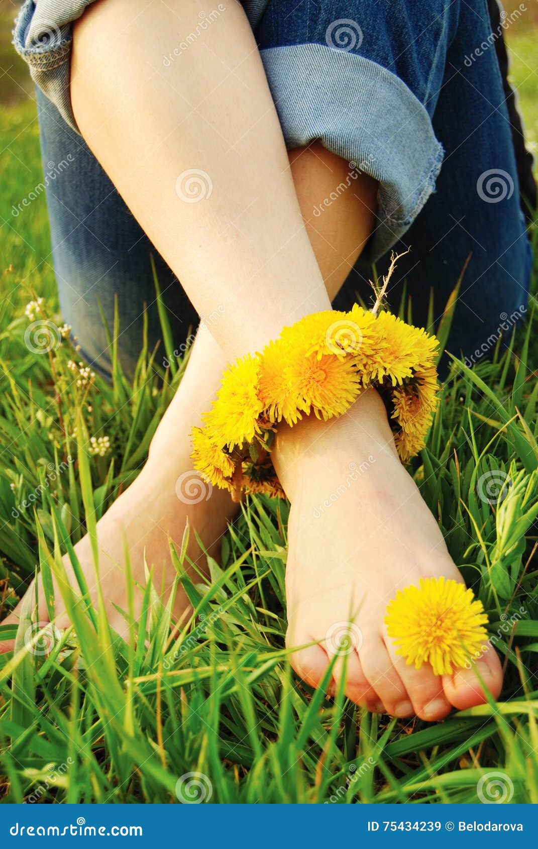 feet of young woman on the grass adorned with dandelions