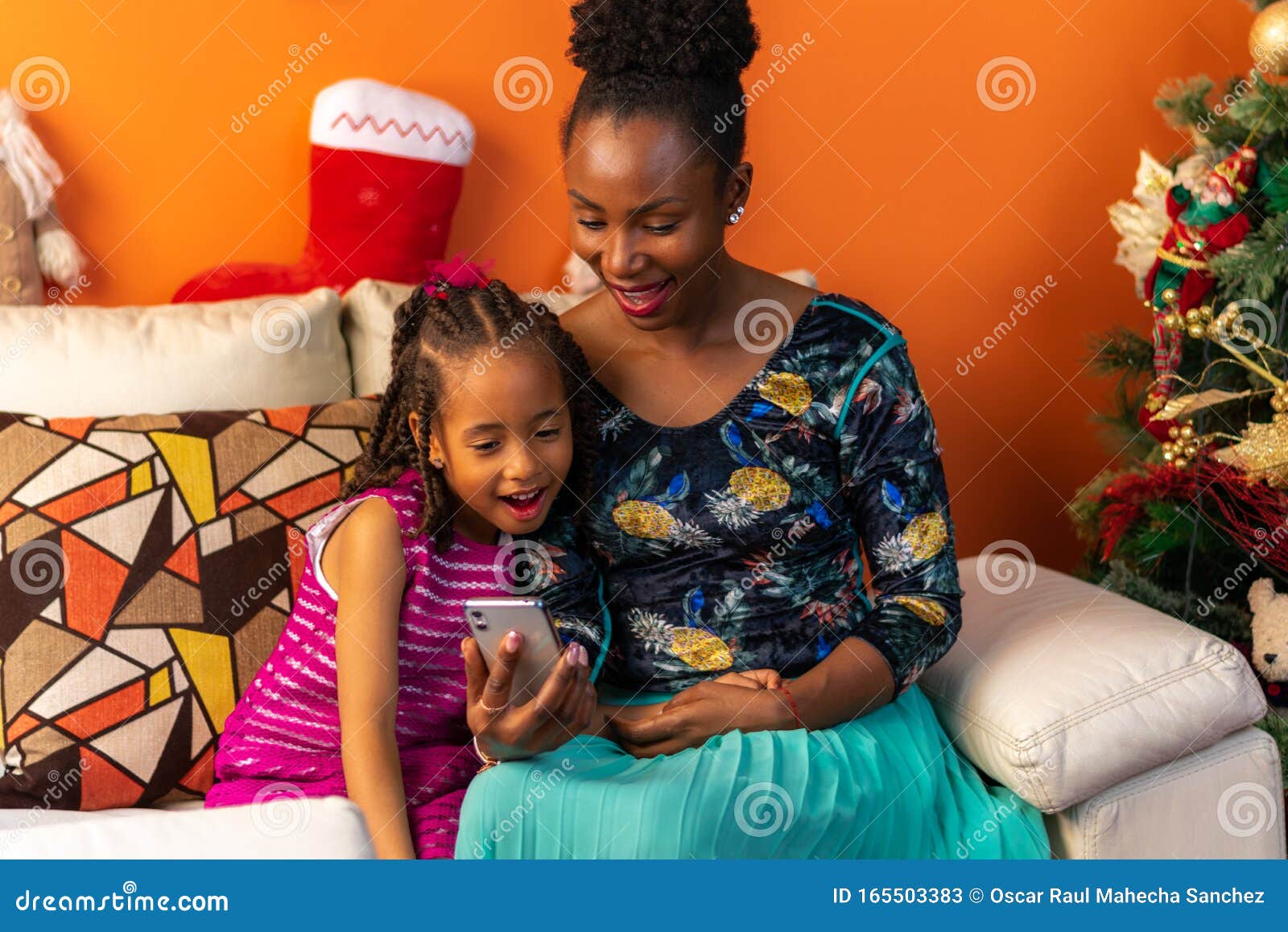 Natale In Latino.Felice Latino Afro Discendente Colombiana Madre E Figlia Sedute Sul Divano Accanto All Albero Di Natale A Controllare Il Cellular Immagine Stock Immagine Di Africano Domestico 165503383