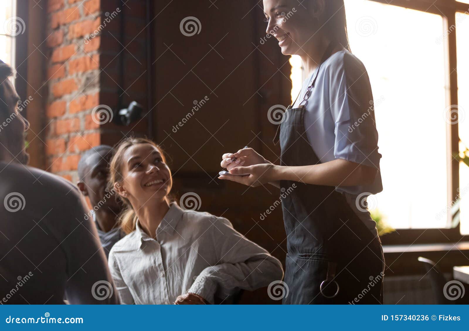 Garçonete bonita servindo grupo de amigas com comida no