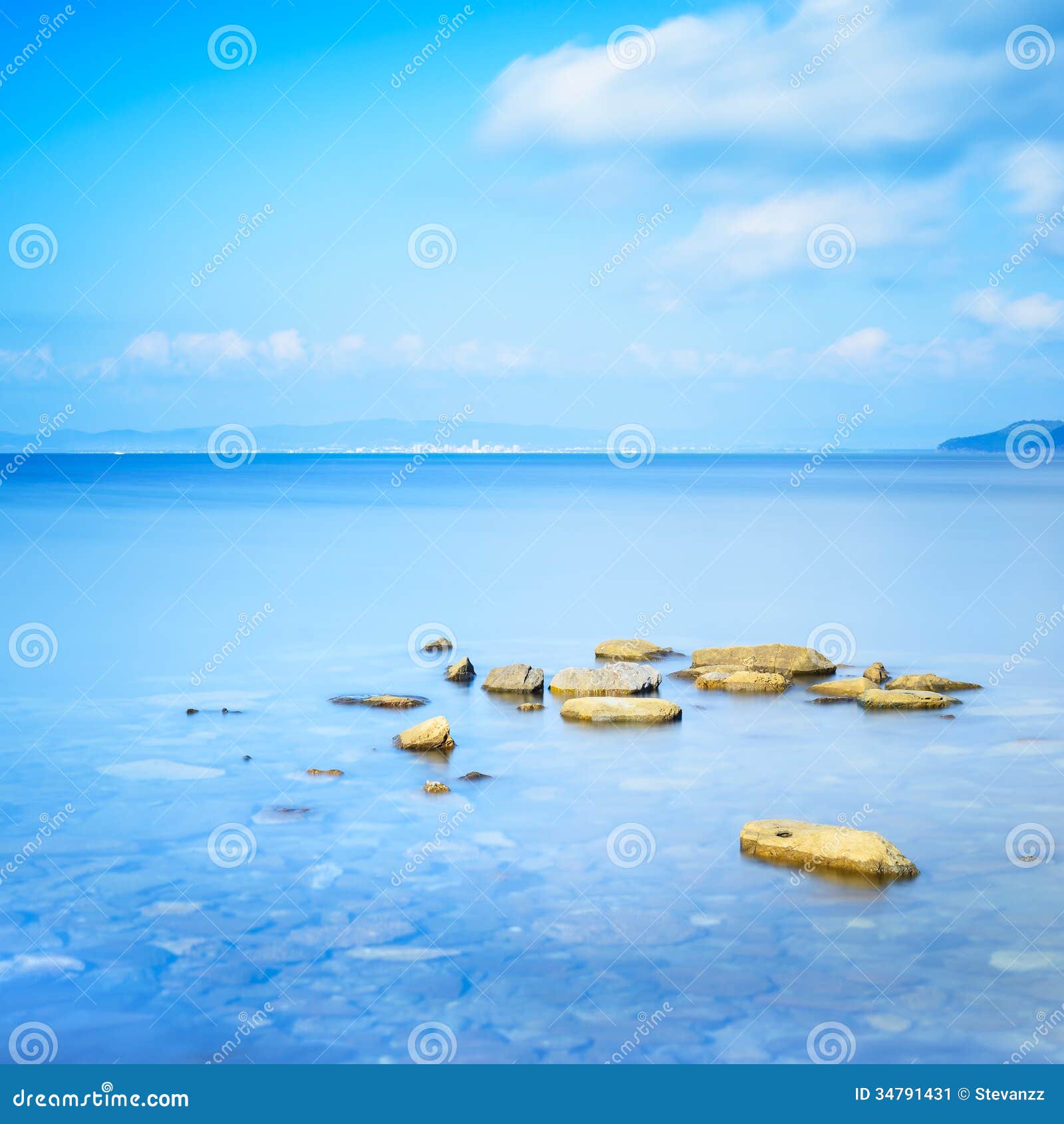 Felsen in einem blauen Ozean in einem Meer bellen. Punta-Ala, Toskana, Italien. Felsen in einem blauen Ozean in einem Meer bellen. Lange Belichtungsphotographie. Punta-Ala, Toskana, Italien