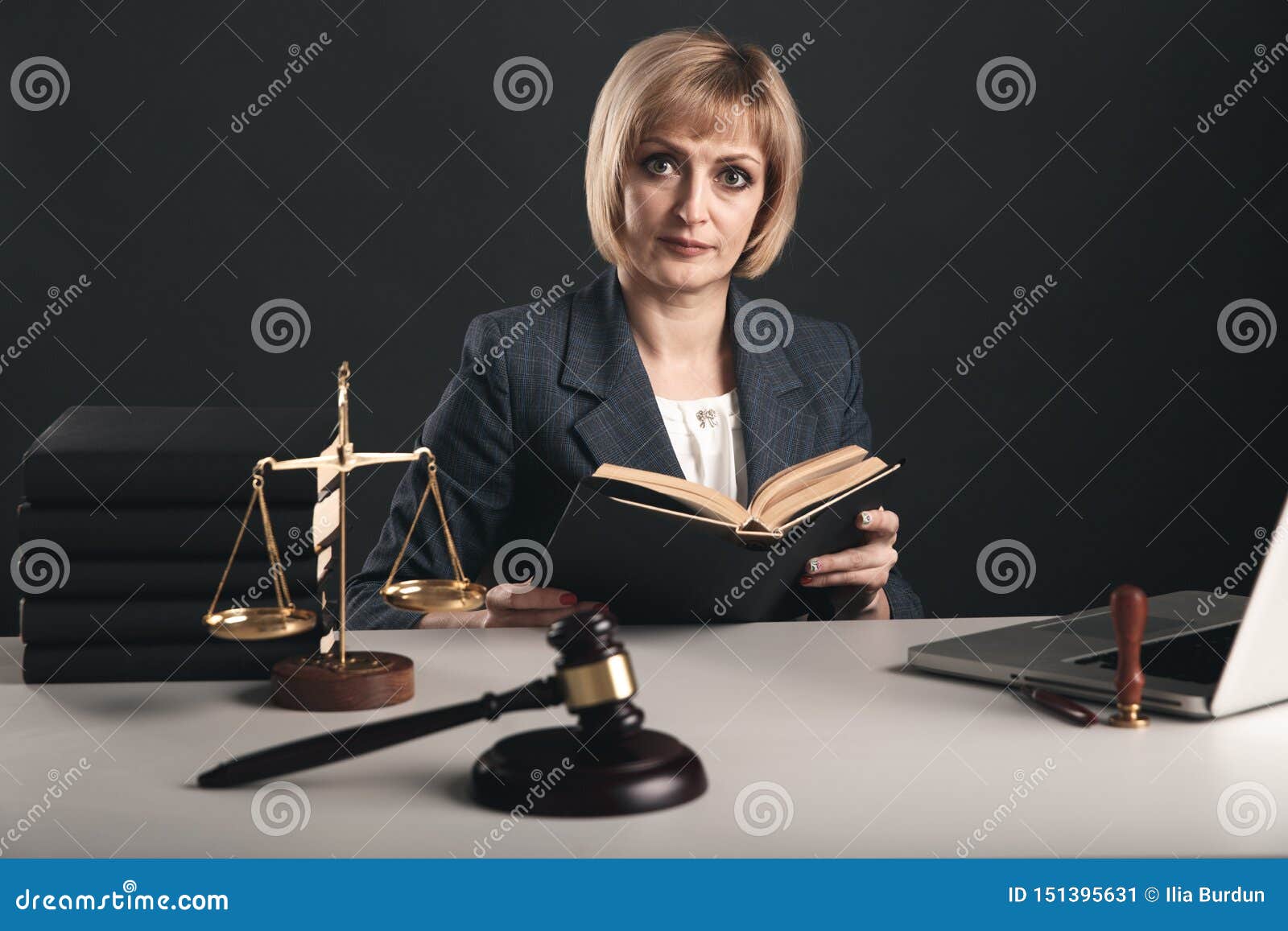 female advocate with juridical books at her workplace. gavel and libra on the desk.