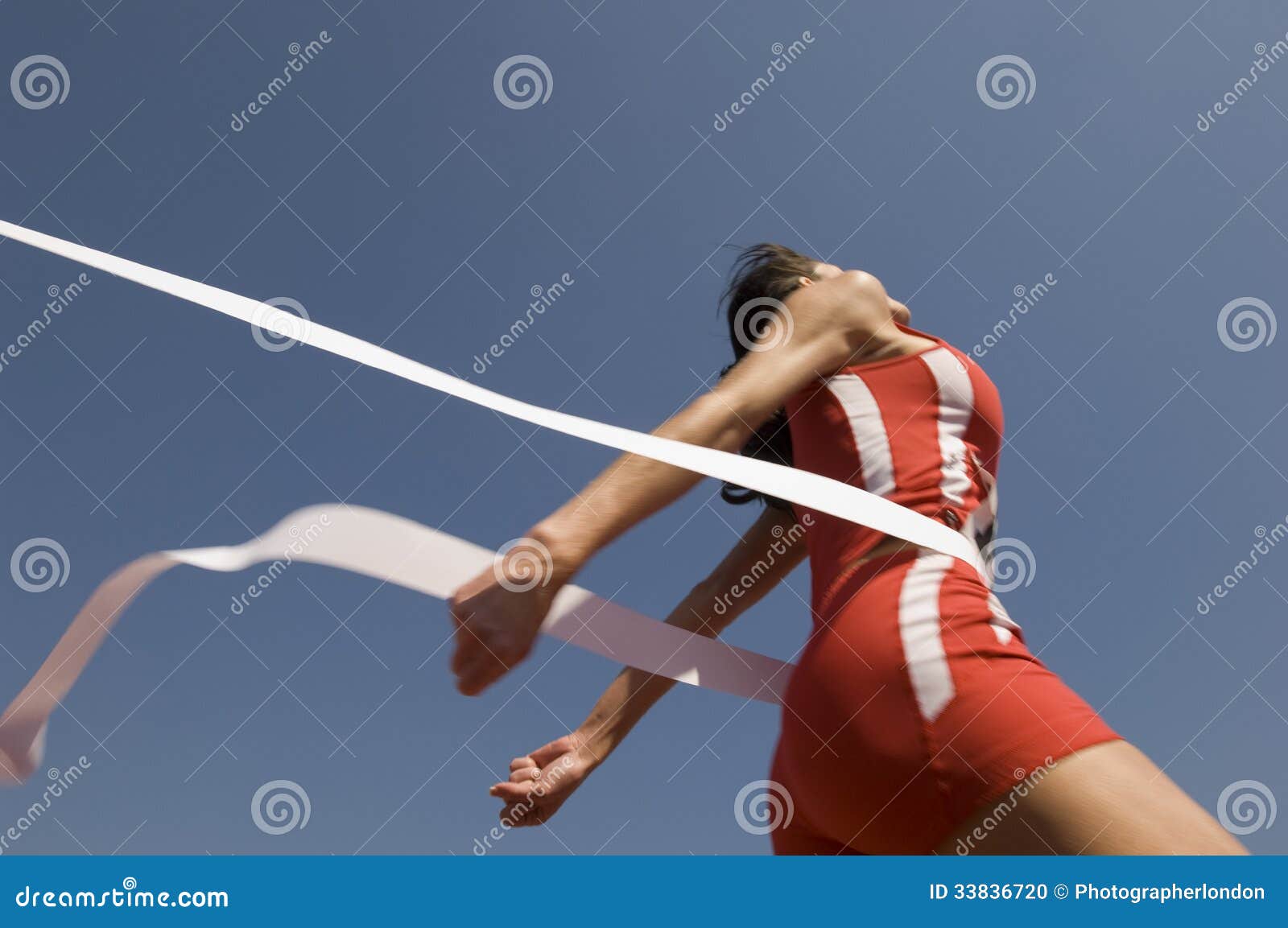 female athlete crossing finish line against blue sky
