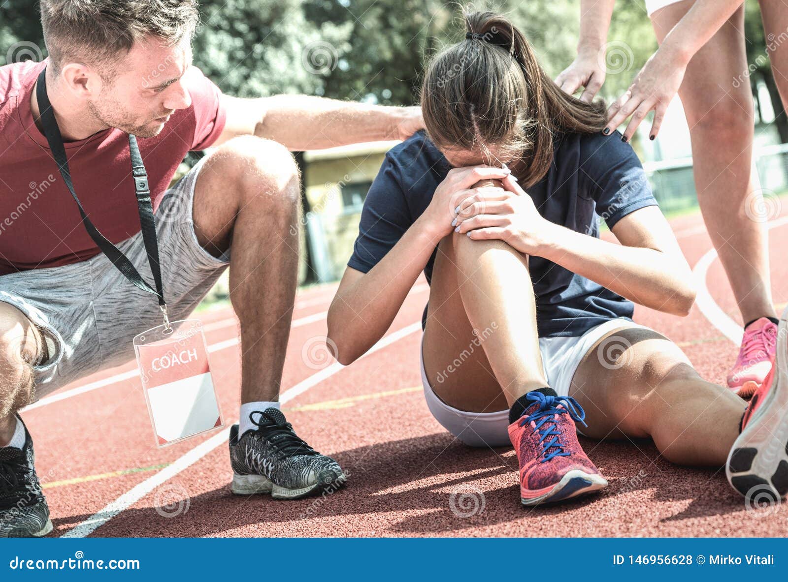 female athlete getting injured during athletic run training - male coach taking care on sport pupil after physical accident