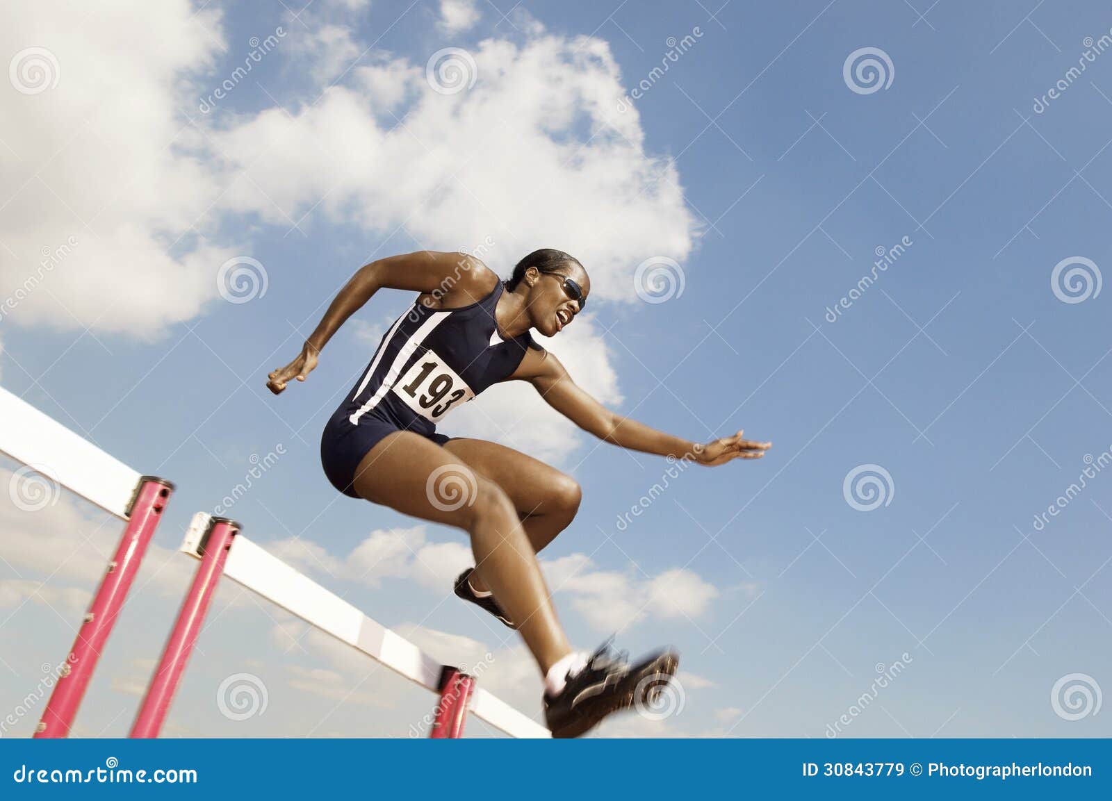 female athlete jumping hurdle