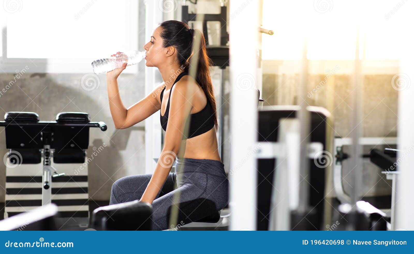 female athlete taking rest and drinking woter after exercising at gym. fitness healthy lifestye and workout at gym concept