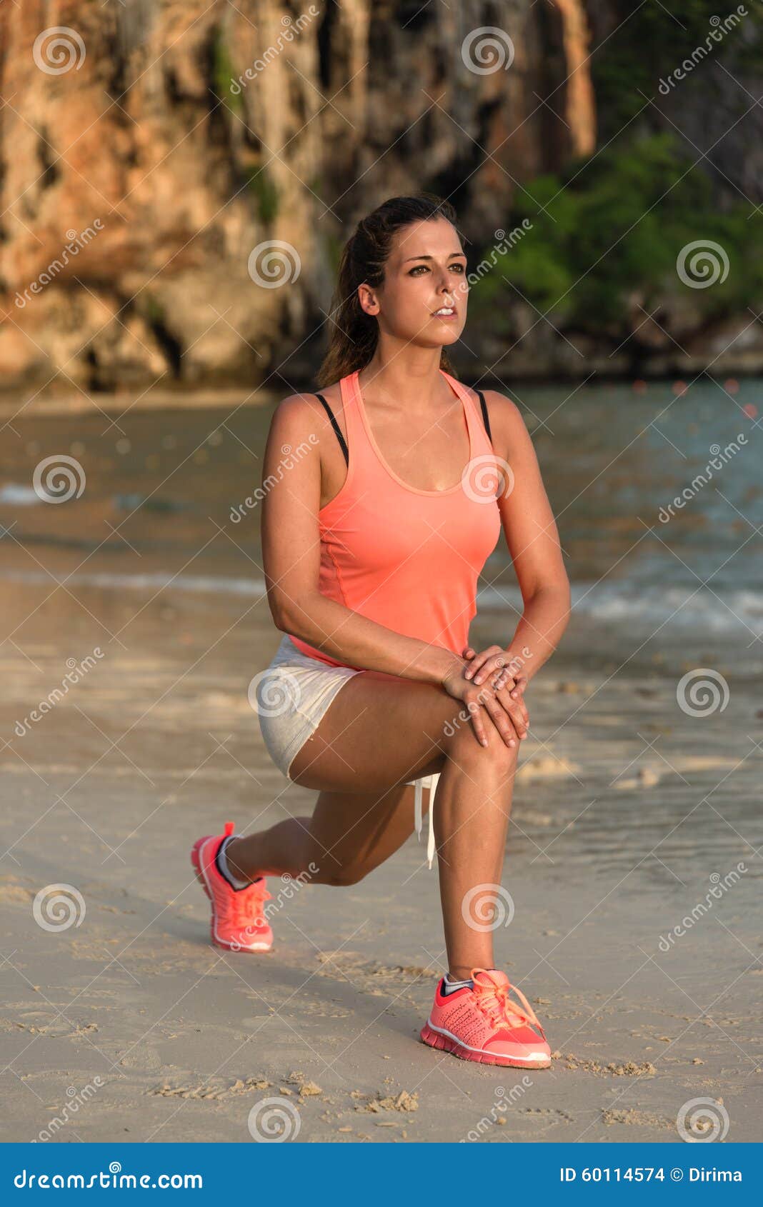 Female Athlete Warming Up and Stretching at the Beach Stock Photo