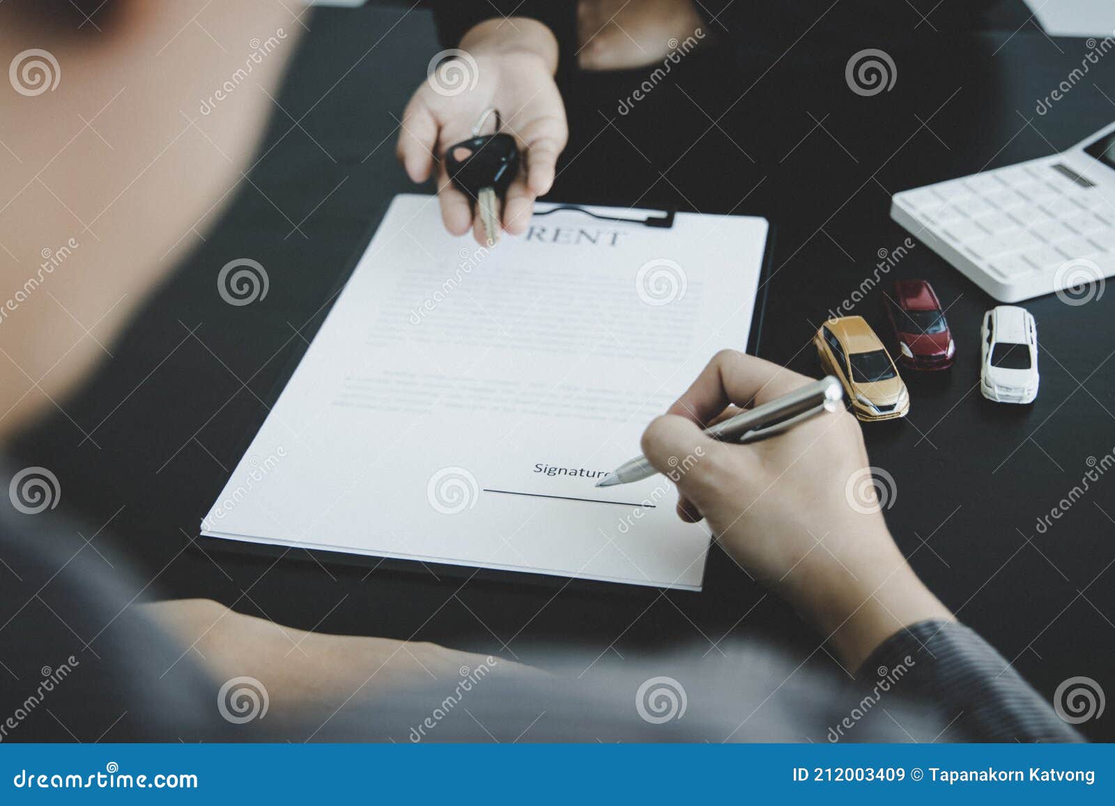 female attendant handed over the rental car key to the customer who signed the contract and the terms of the agreement on the docu