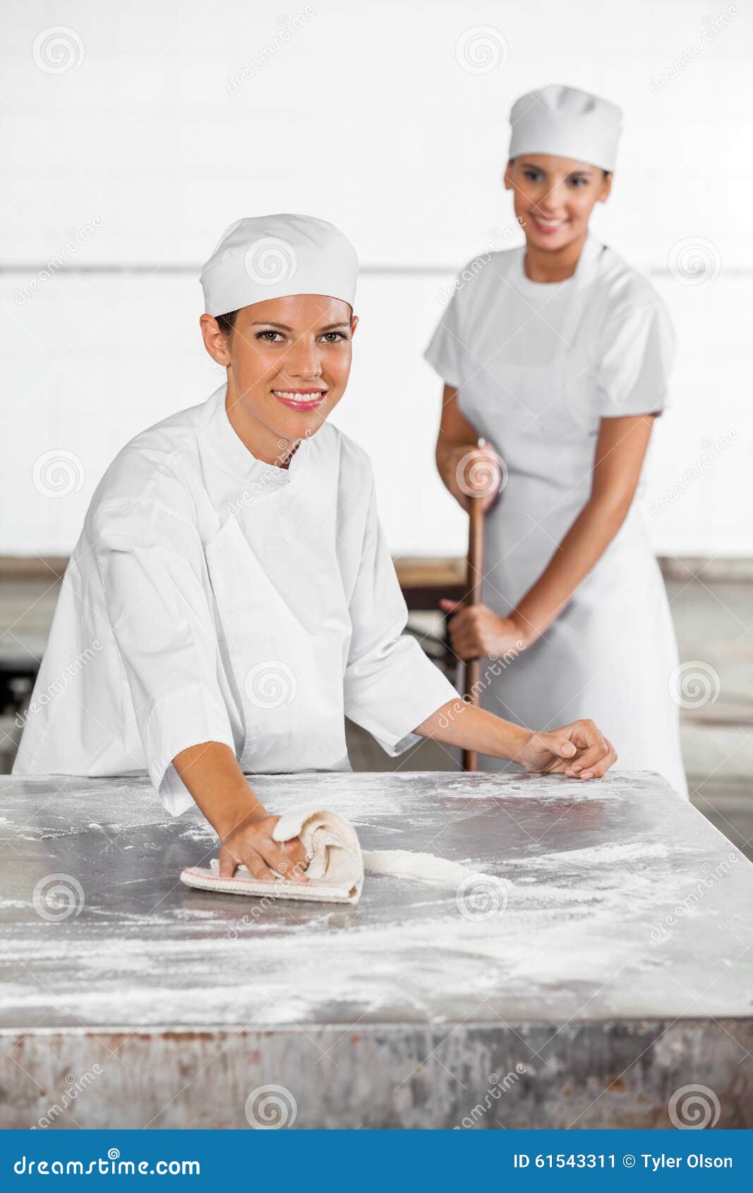 Female Baker Cleaning Table while Colleague Using Stock Image Image