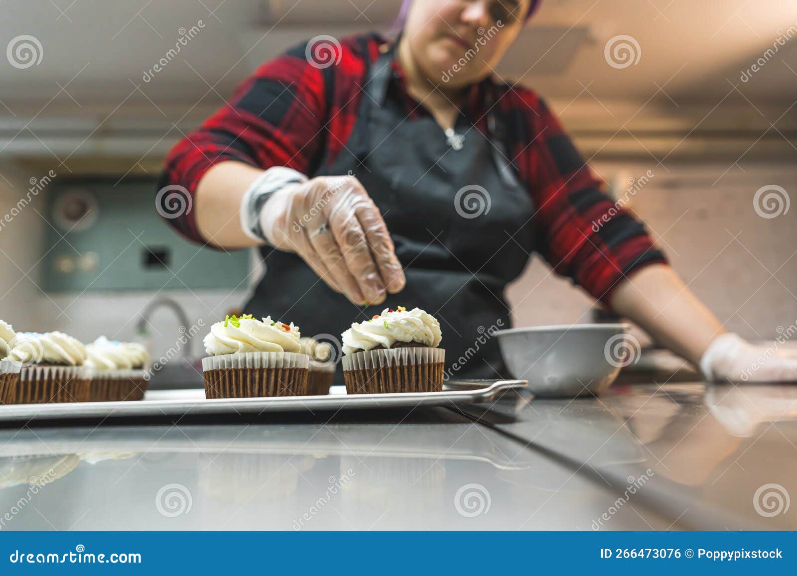 Female Baker Wearing Glove and Black Apron Decorating Chocolate Frosted ...