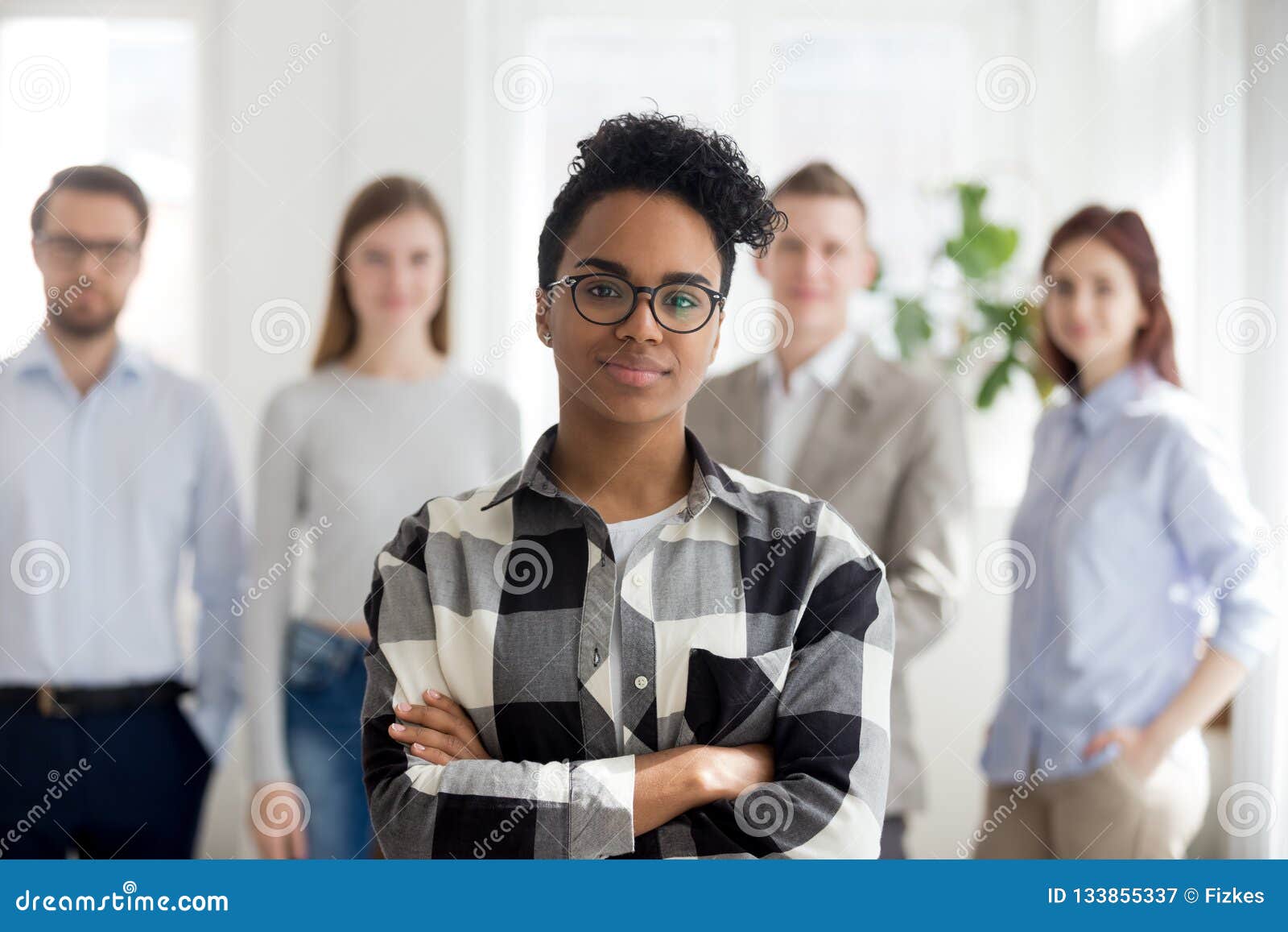 female black millennial employee standing foreground arms crosse