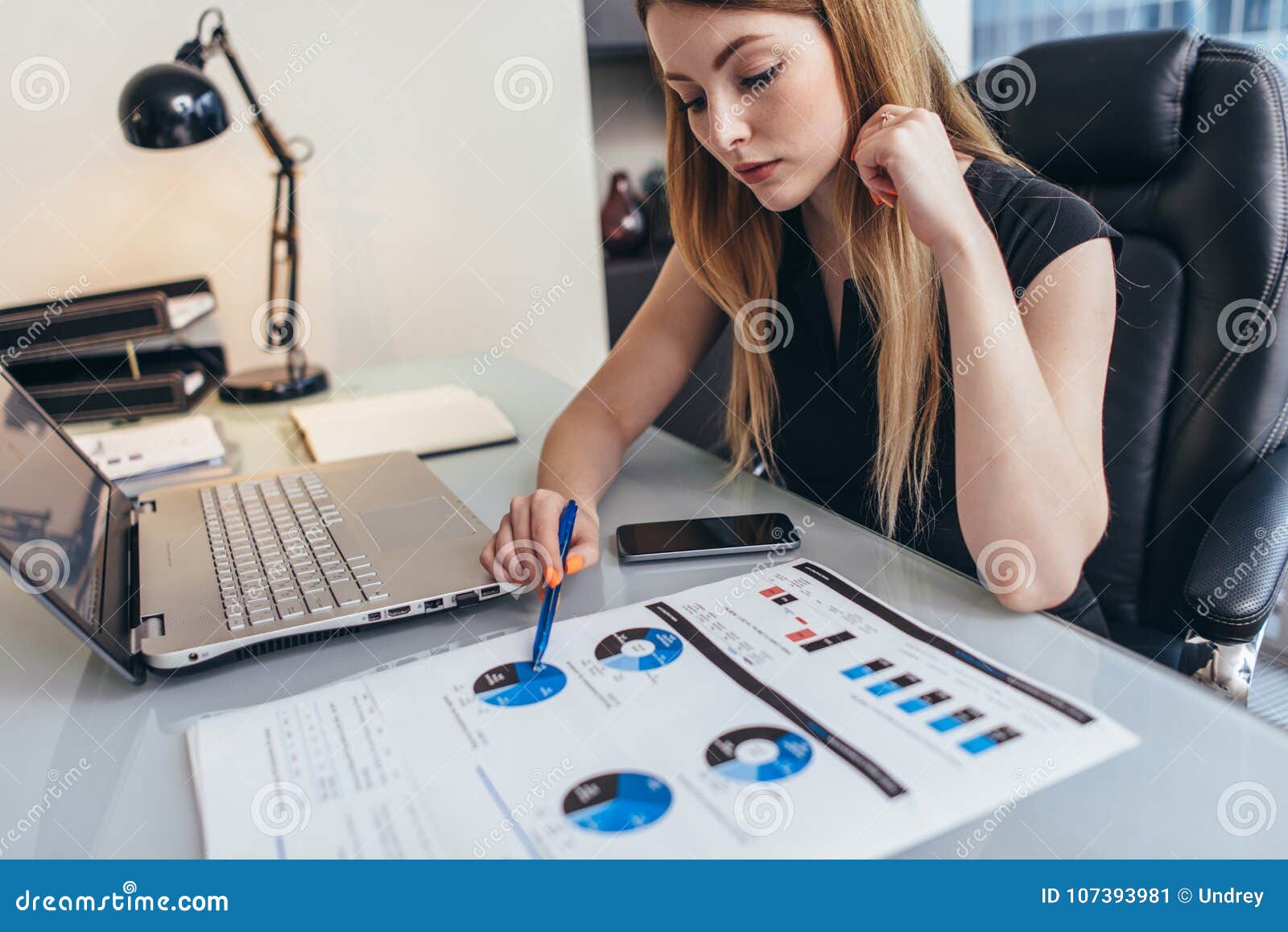 female businesswoman readind financial report analyzing statistics pointing at pie chart working at her desk