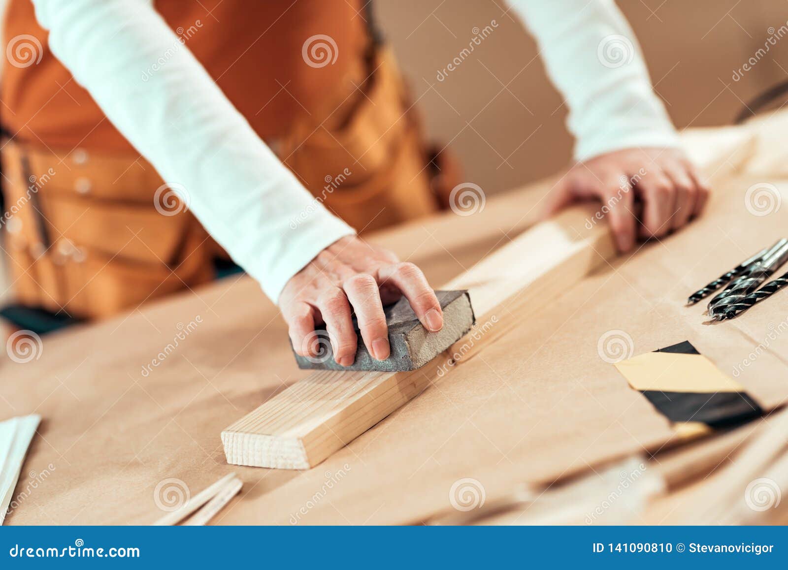 female carpenter manually sanding wooden plank