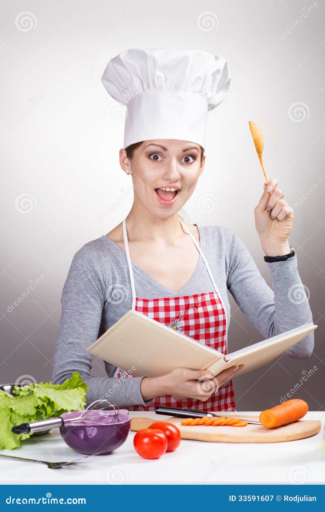 Female Chef With The Cookbook And A Wooden Spoon On Gray ...