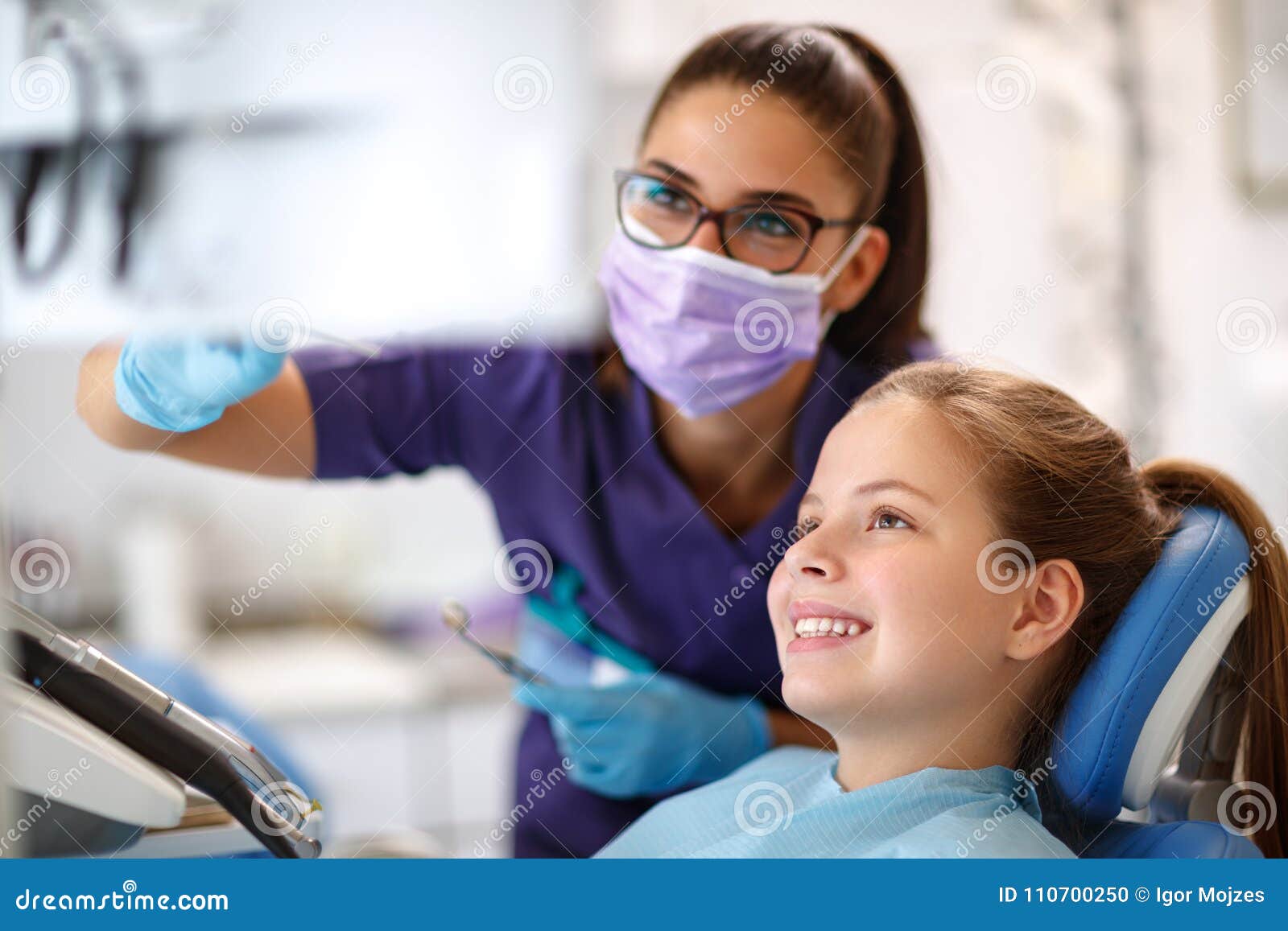 child in dental chair with female dentist looking at dental foot