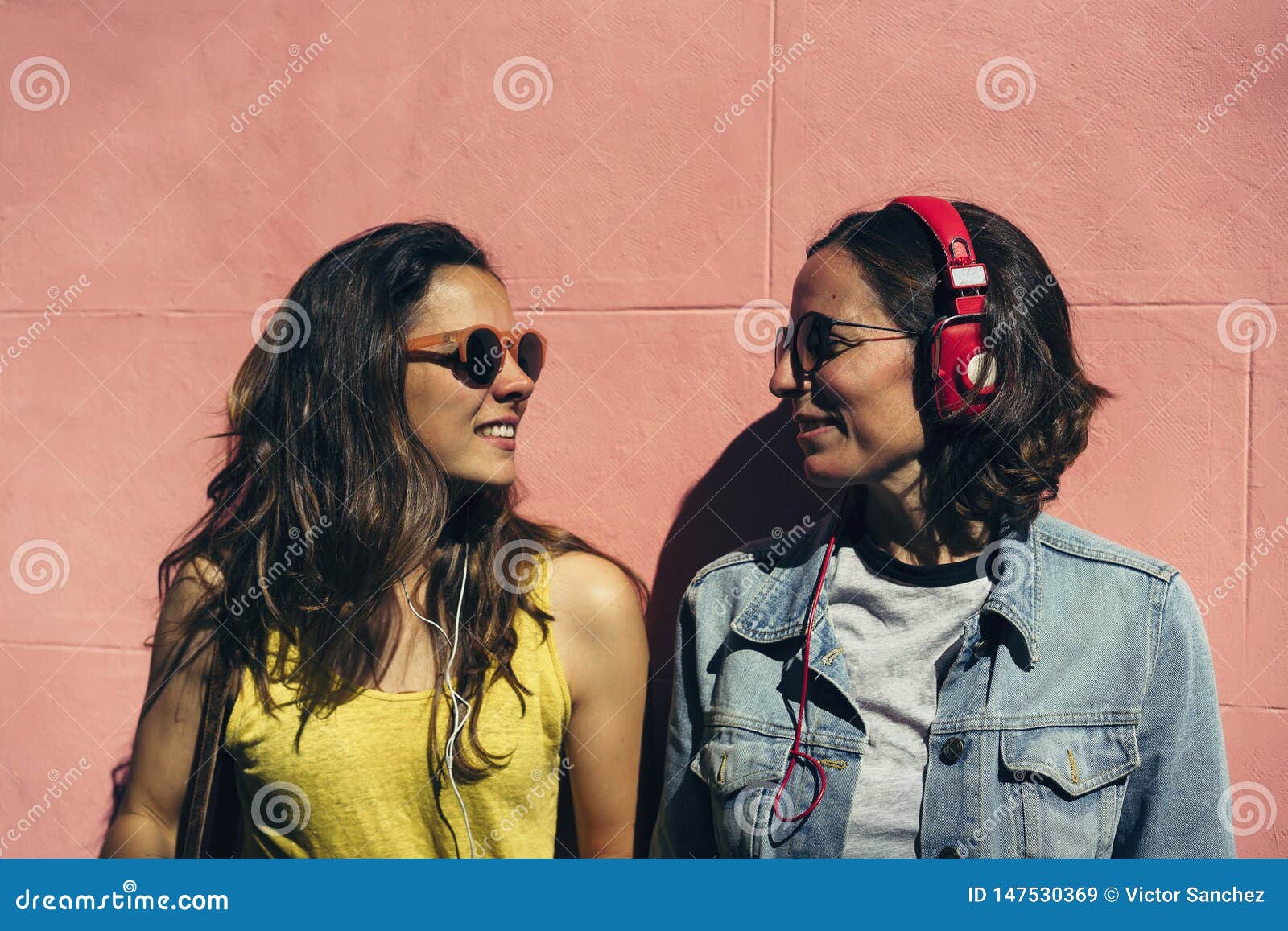 Female Couple Listening Music and Spending Time Together in a Pink Wall