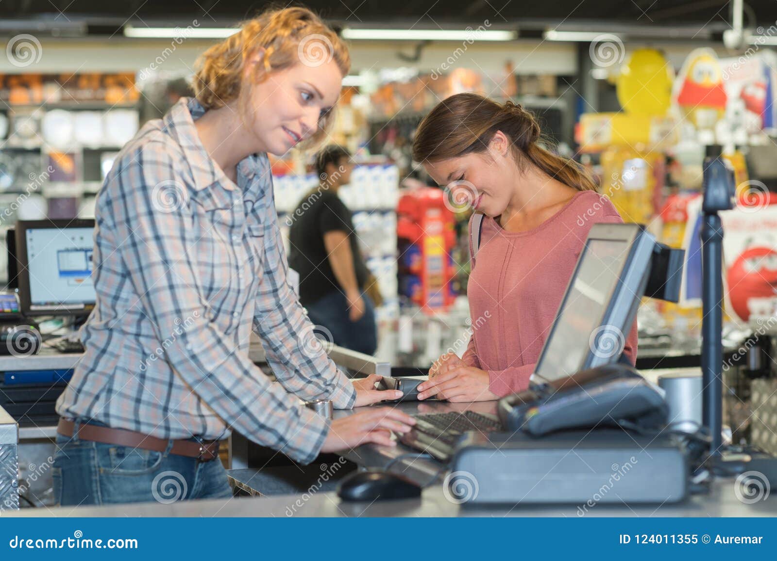 Female Customer Paying At Cash Desk With Terminal In Supermarket