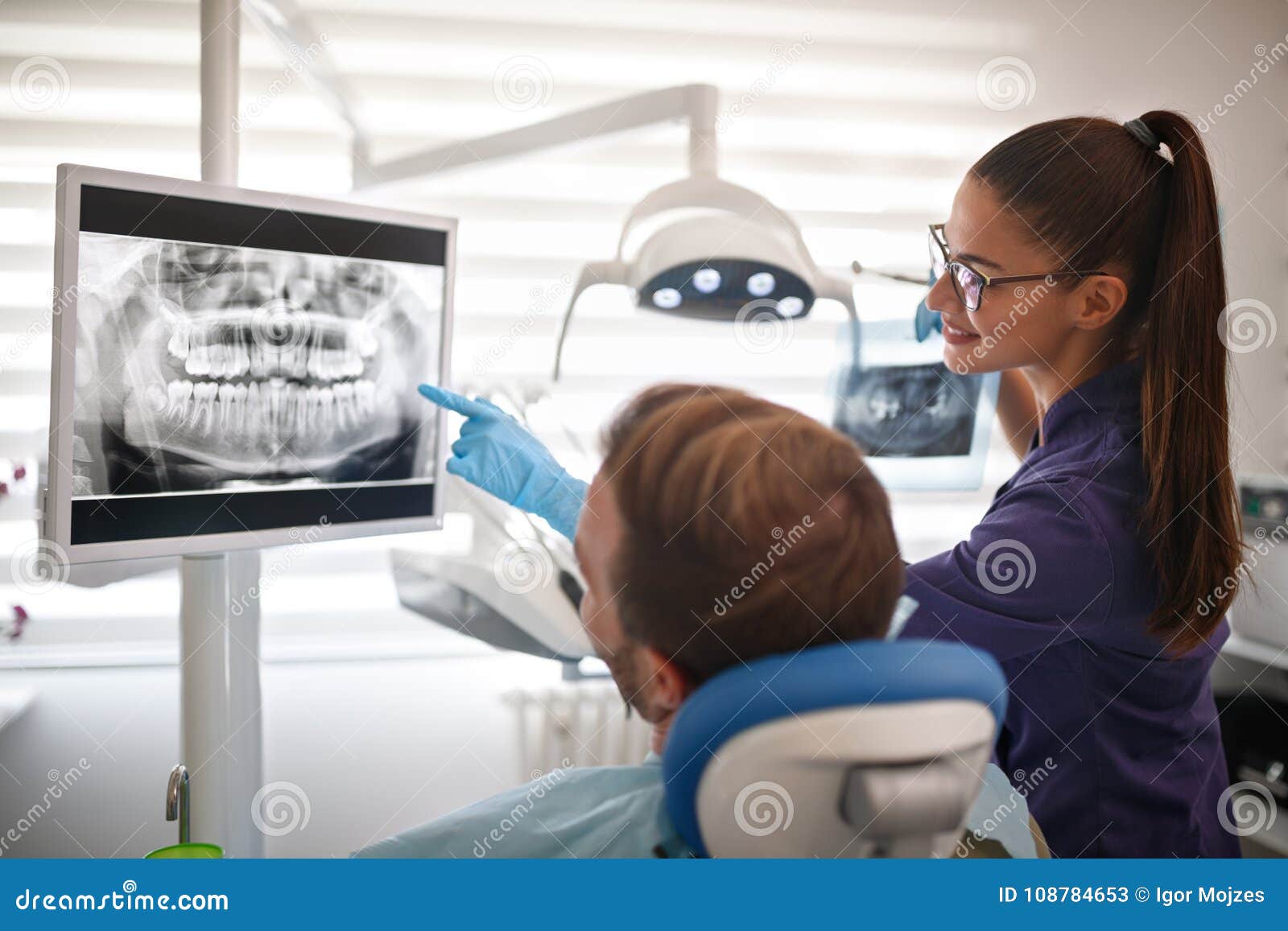 dentist showing x-ray footage of teeth to patient