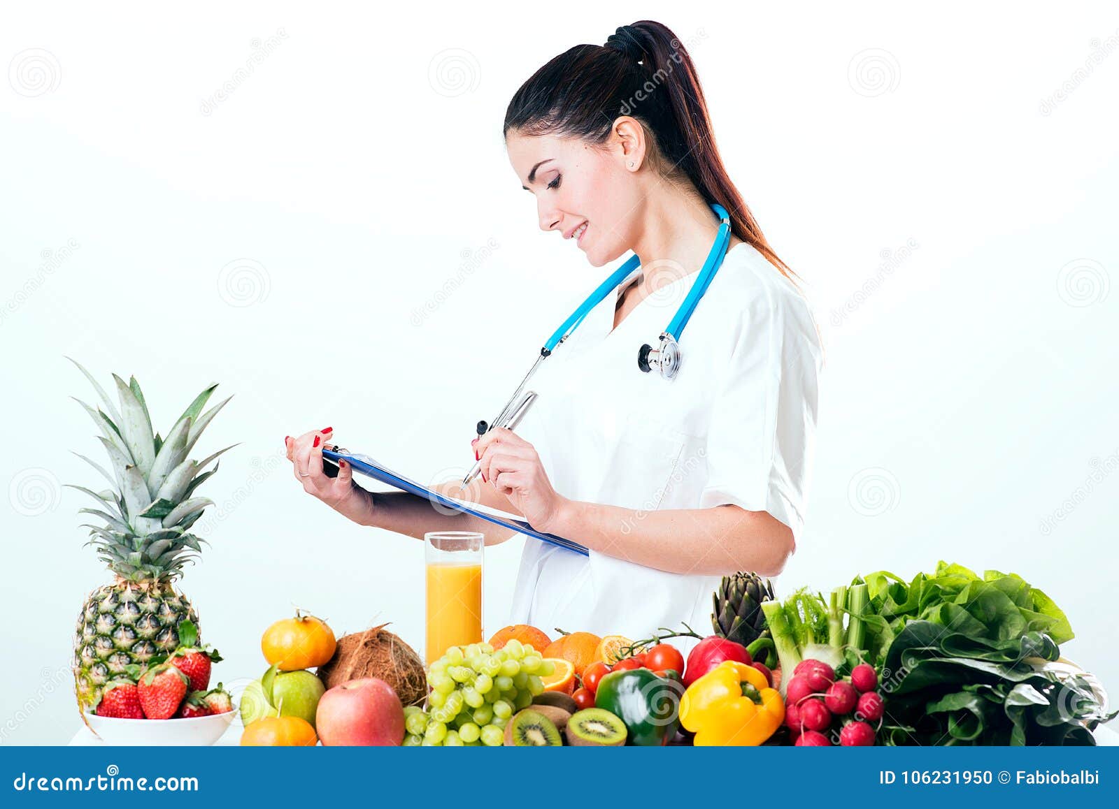 Female dietitian in uniform with stethoscope on a desk with vegetables and fruits