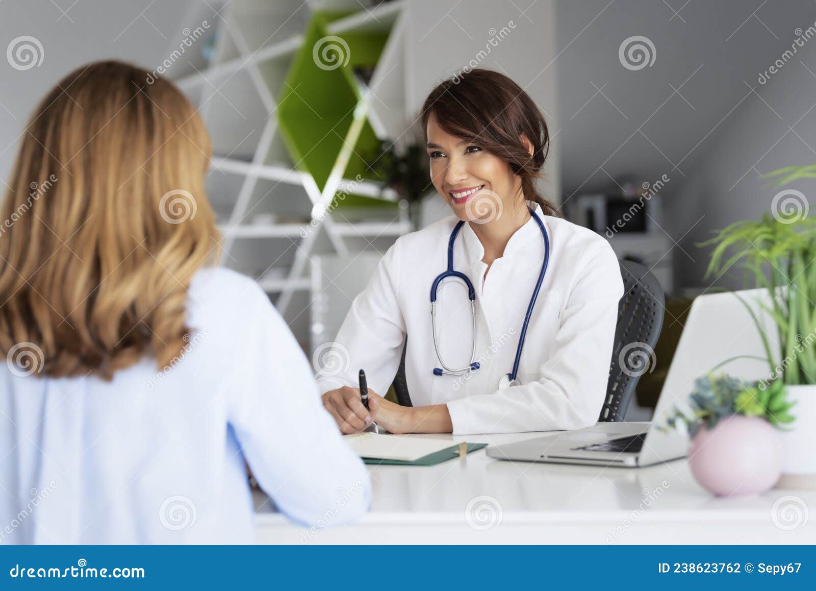 female doctor consulting her patient while sitting at desk in doctor`s office