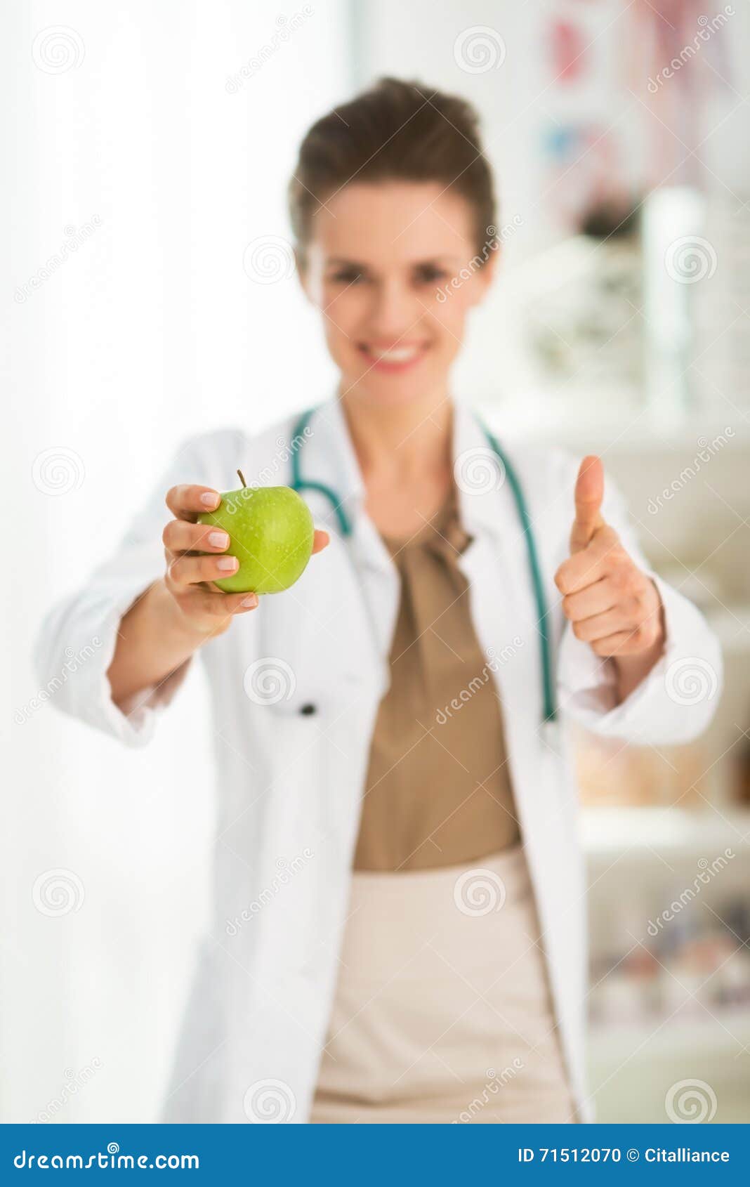 female doctorÃÂ giving green apple and showing thumbs up. closeup