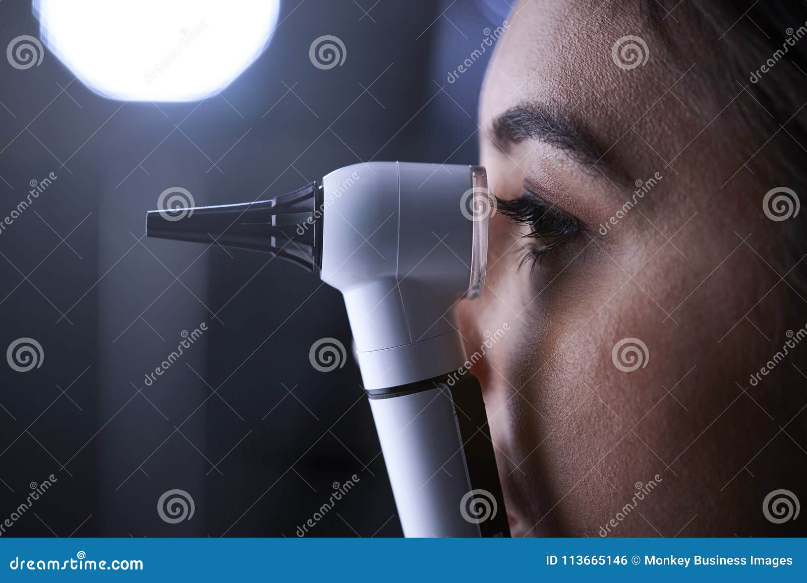 Female Doctor Using Otoscope for Examination, Side View Stock Photo