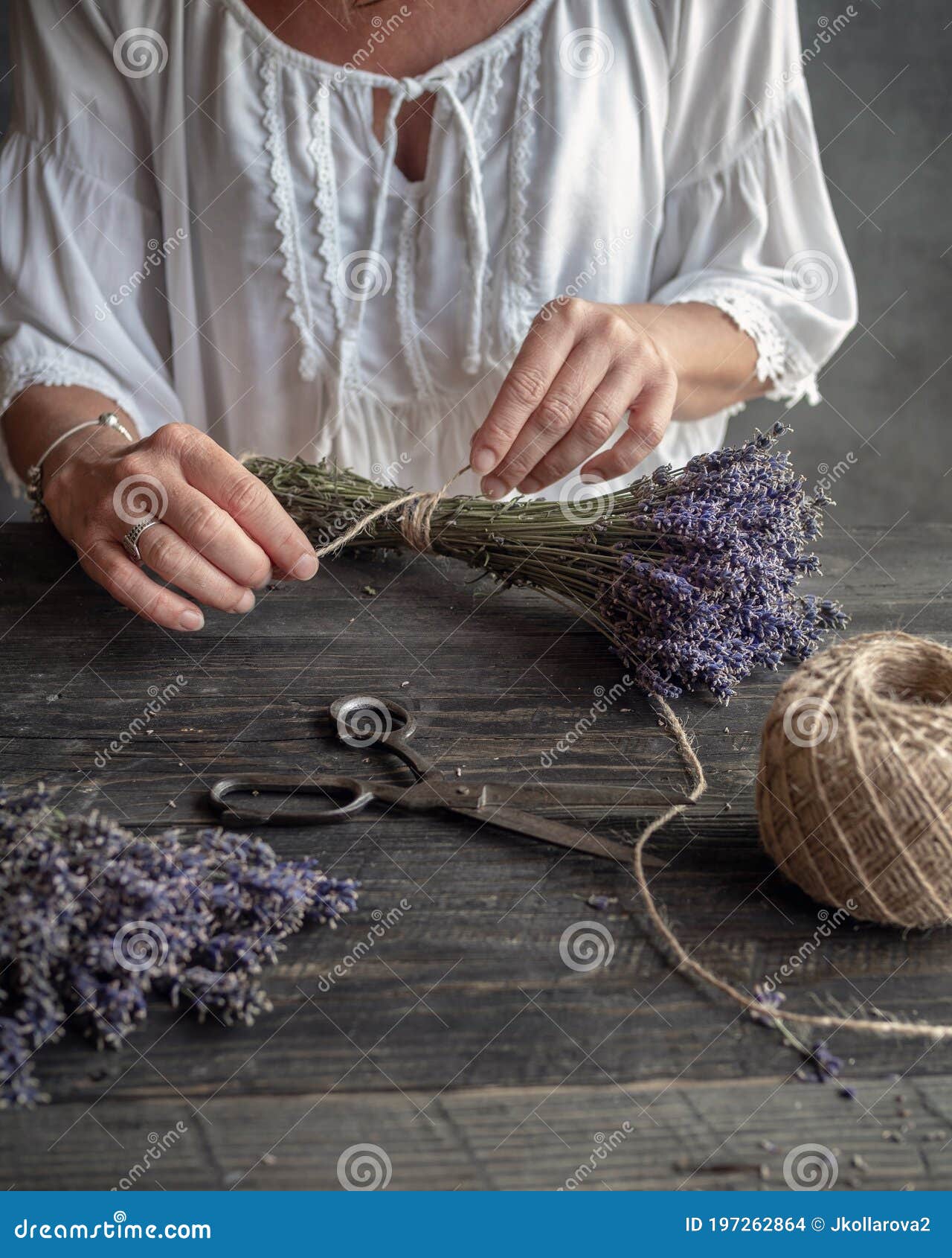 female floristÃ¢â¬â¢s hands tied up bunch of lavender by twine. working table