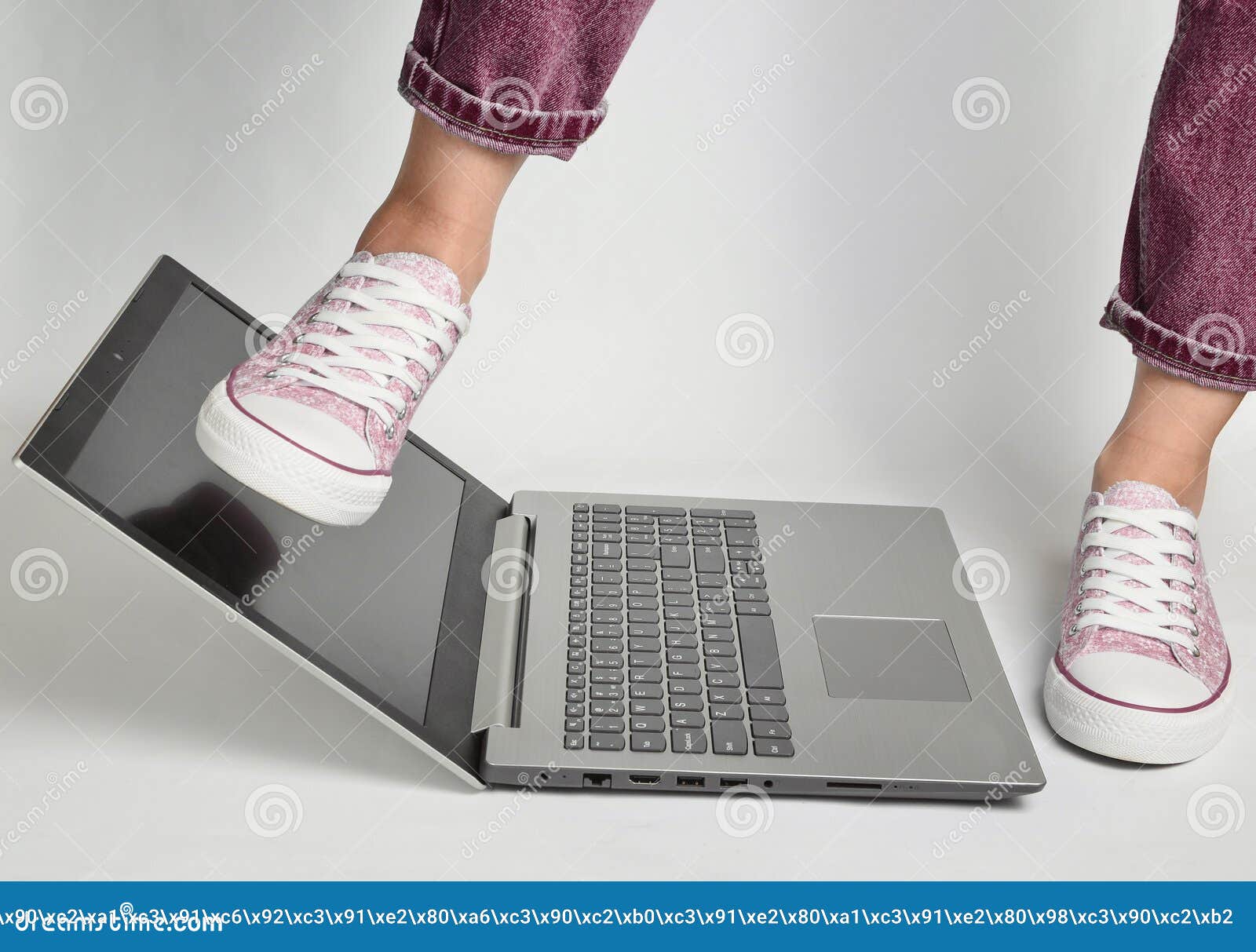 Female Foot in Jeans and Sneakers Comes with a Foot on the Laptop on a ...