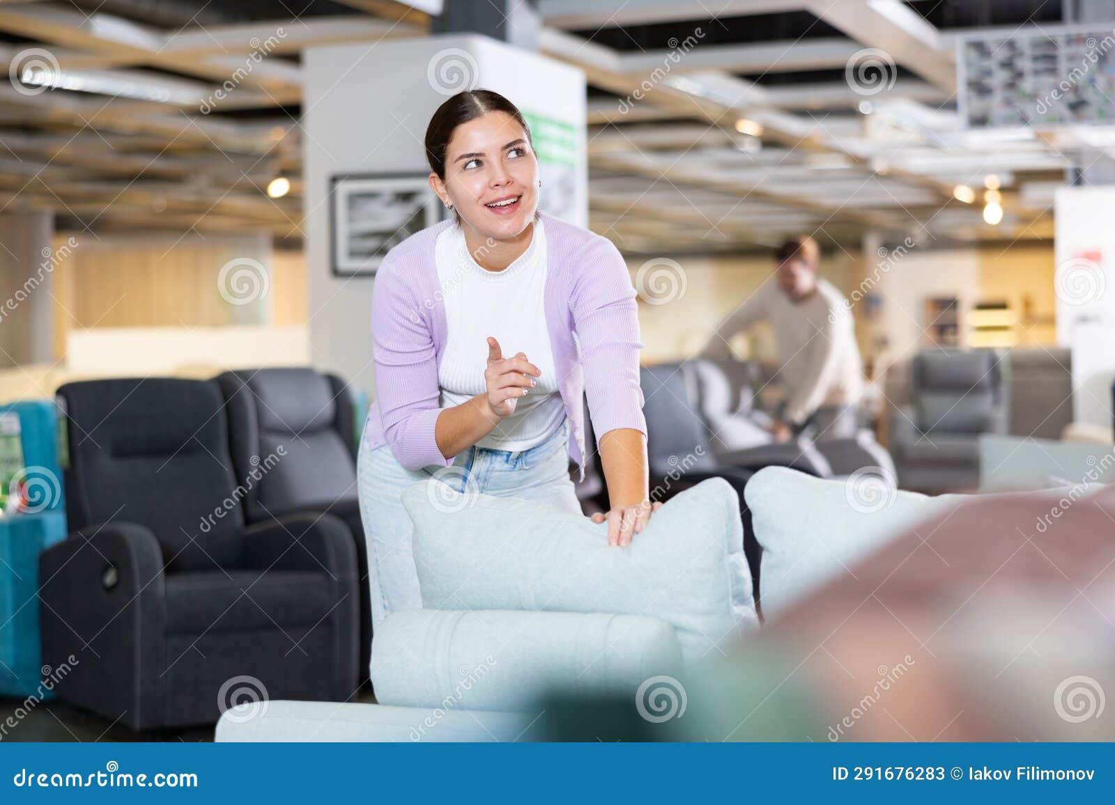 Female Furniture Salesperson Showing Armchairs for Sale in Furniture