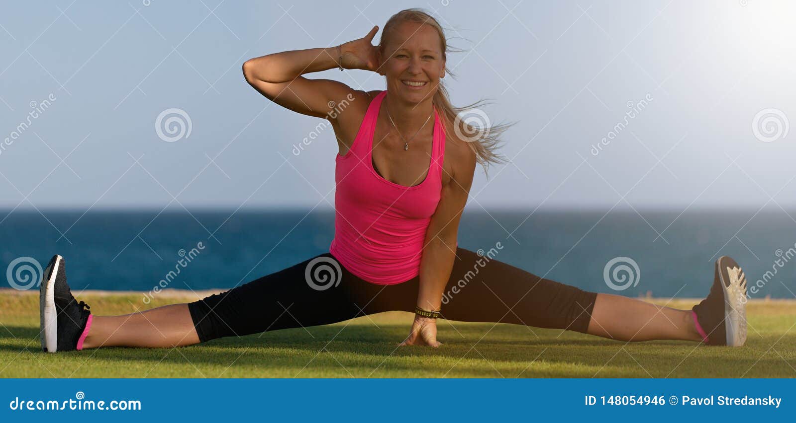 Female Gymnast in Sportswear, Does Leg Split, Sits on Grass on Ocean Coast,  Poses in Yoga Stock Photo - Image of cross, adult: 148054946
