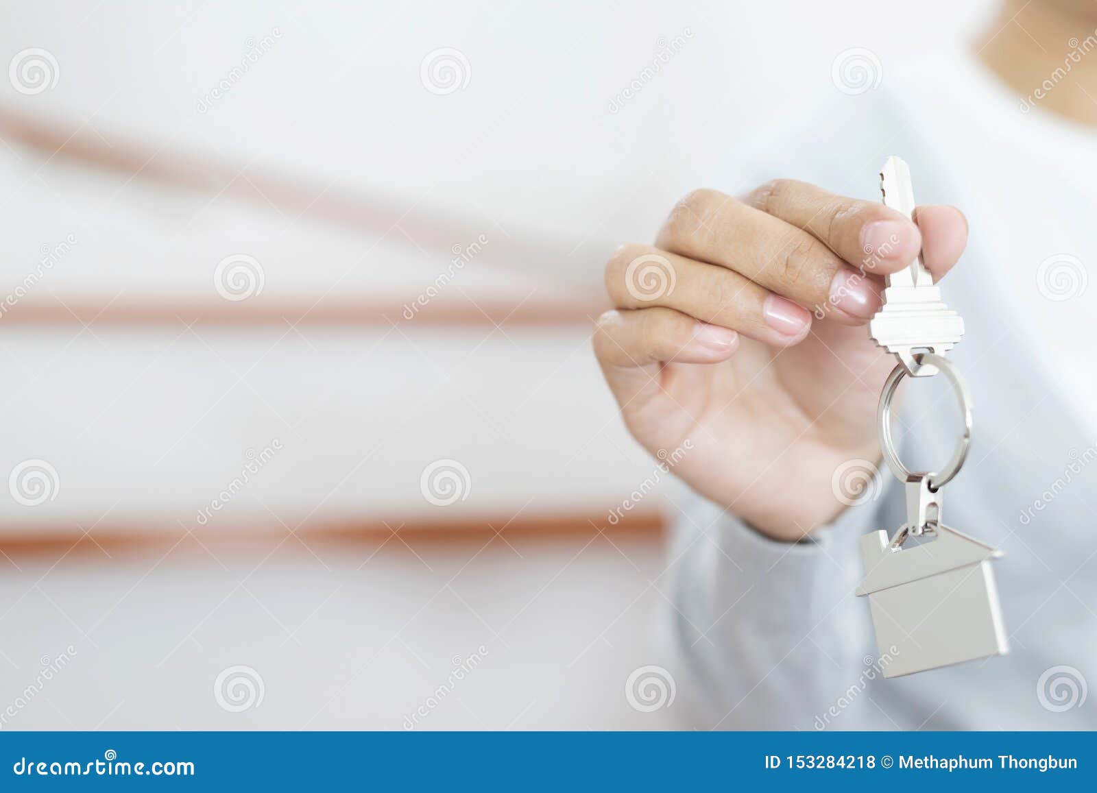 female hand holding house key on home d key chain. concept for buying real estate agent