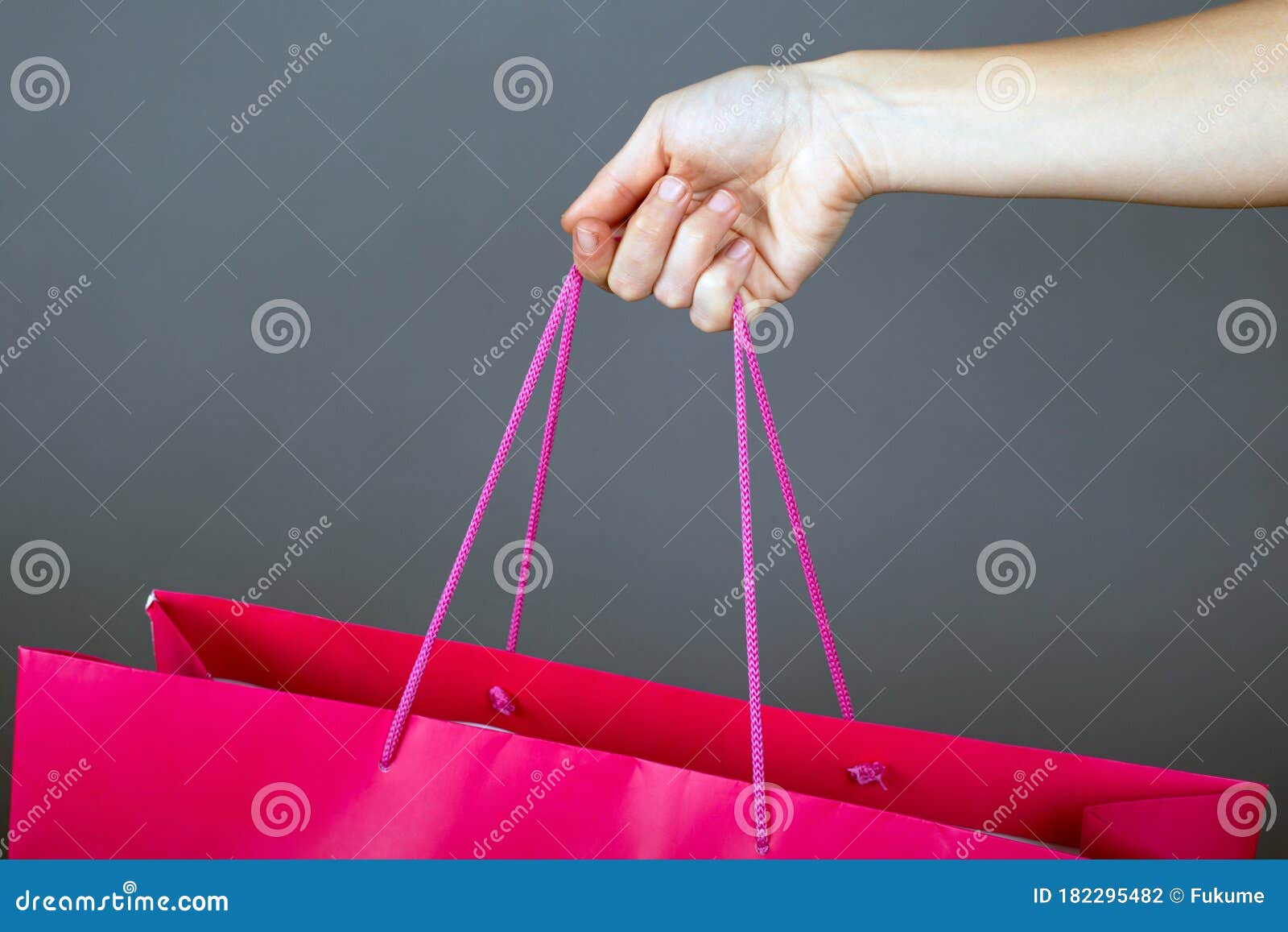 female hand holds pink package on a dark background. purchases shopping gift close-up