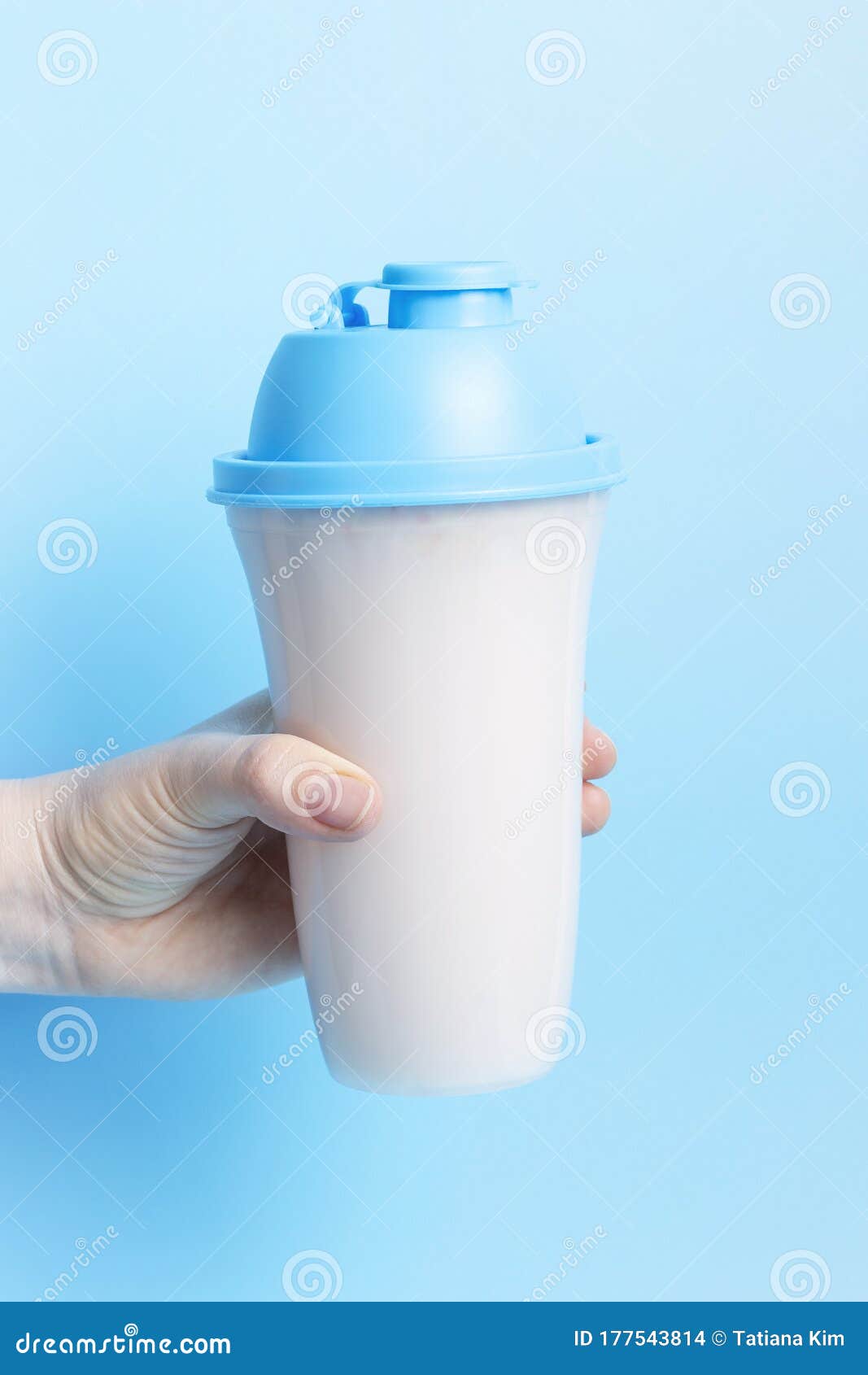 Female Hand Holds a Shaker with a Protein Shake on Blue Background