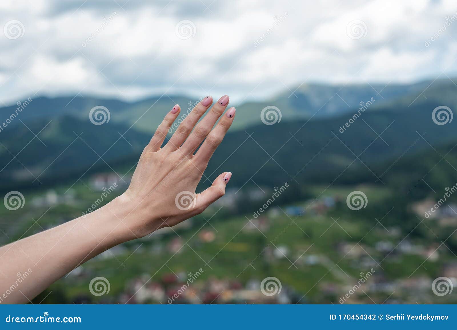 female hand on nature background. reach the mountains. travel manicure