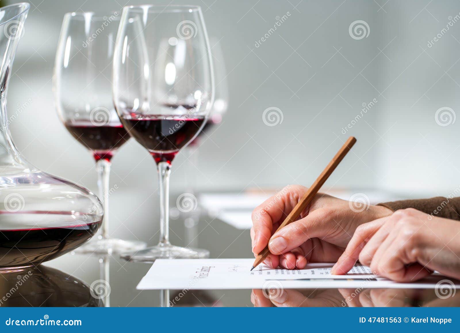female hand taking notes at red wine tasting.
