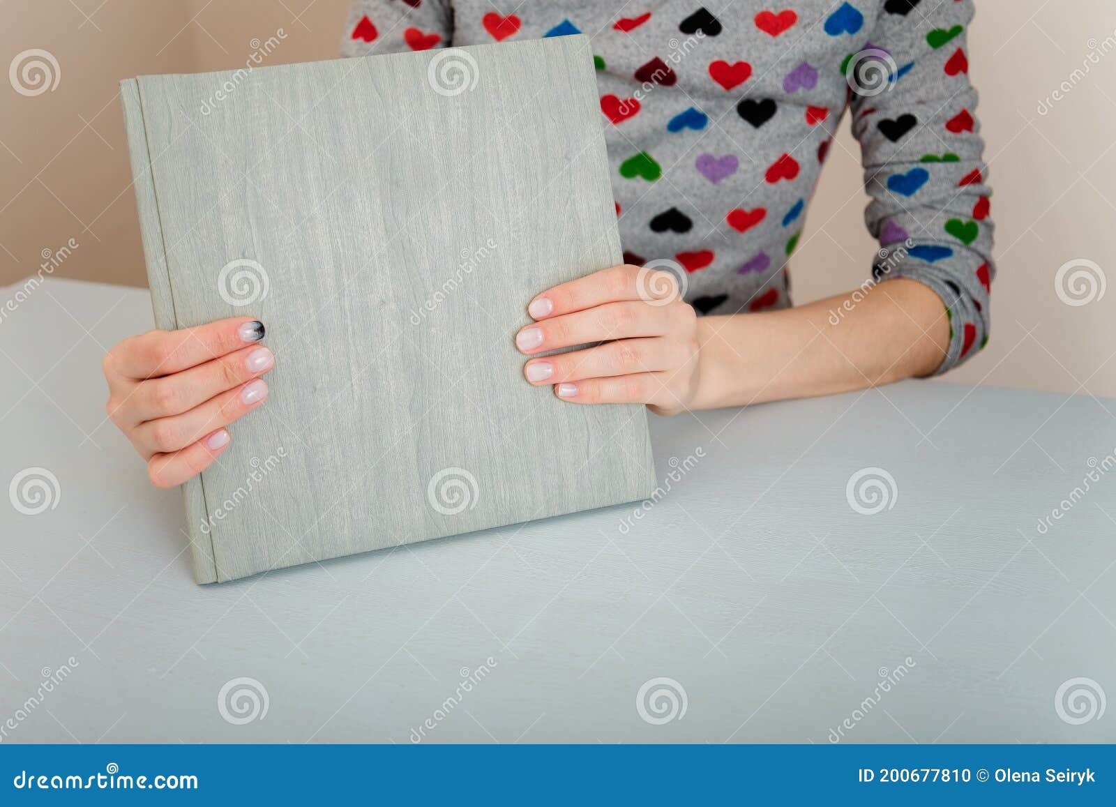 female hands with fir-tree forest manicure holding leather covered album or notebook on white background. christmas