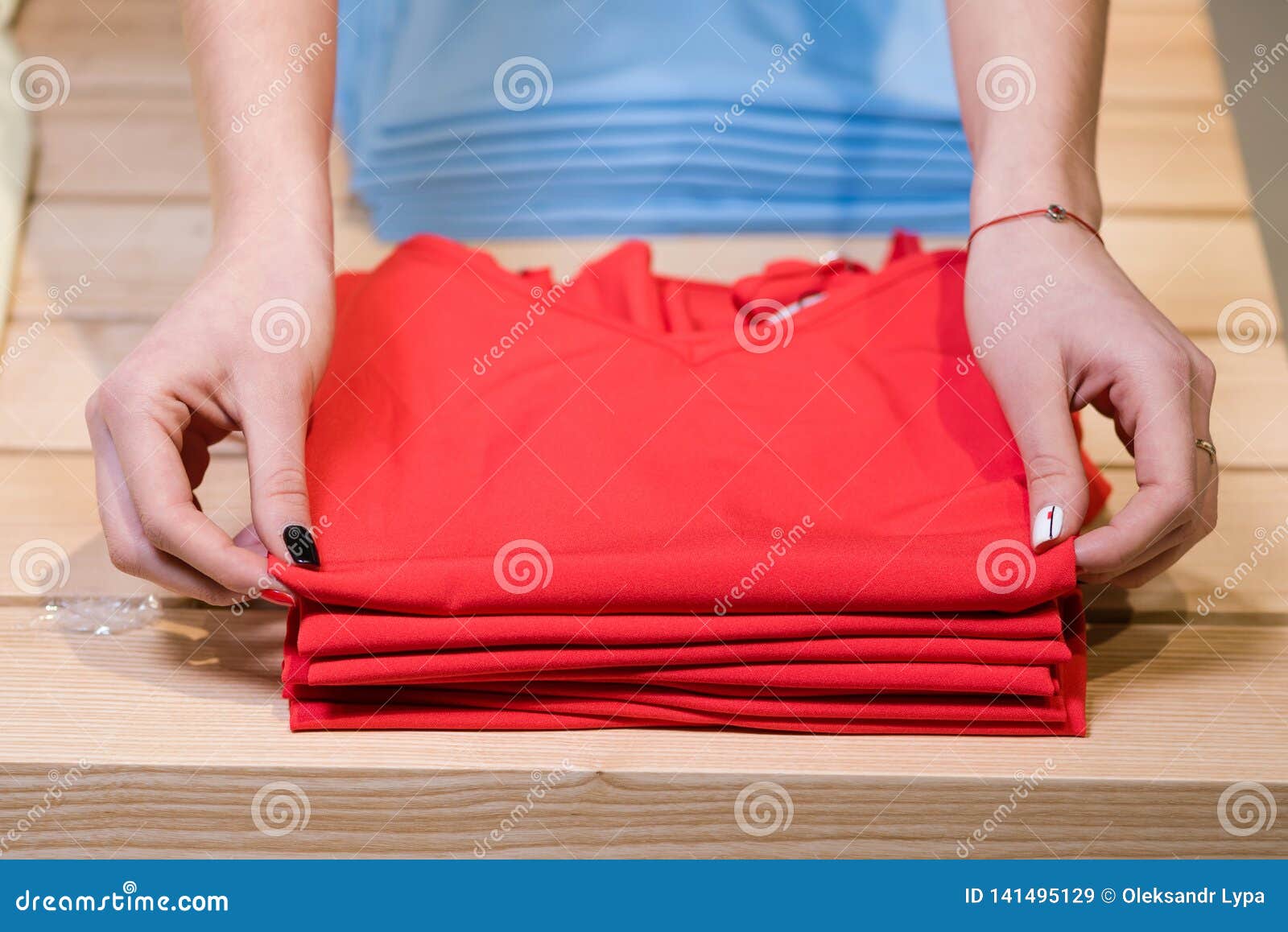 female hands fold red shirts, clothing store