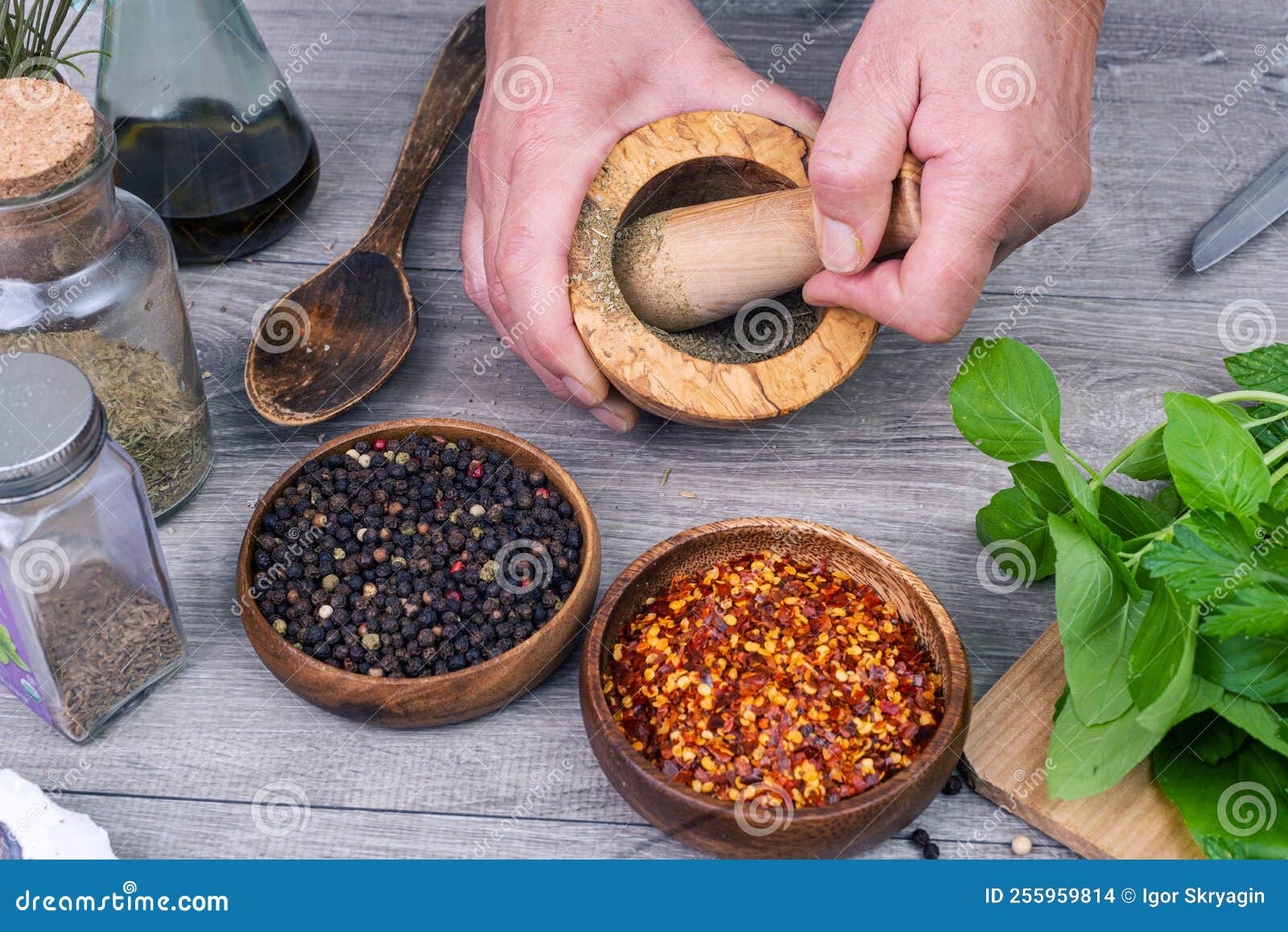 Female Hands Grind Spices in a Mortar on the Kitchen Table Stock Photo