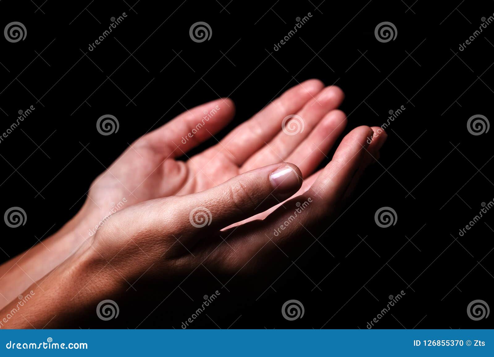 female hands praying with palms up arms outstretched. black background