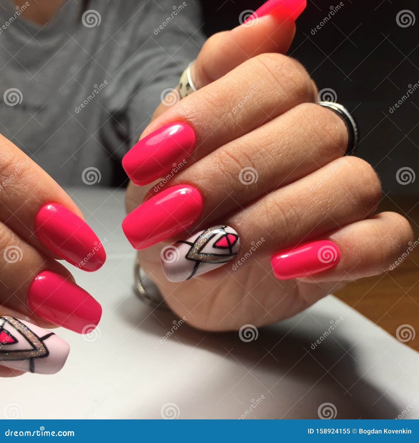 female hands with stylish red manicure on grey background