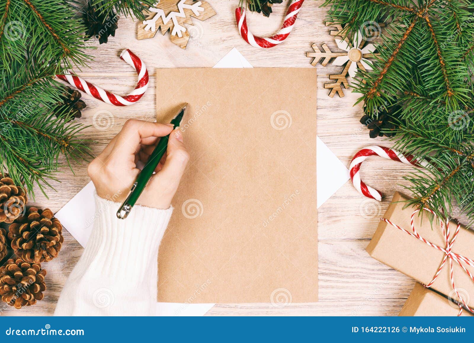 Female Hands Writing A Letter To Santa Claus. Christmas Gifts On A