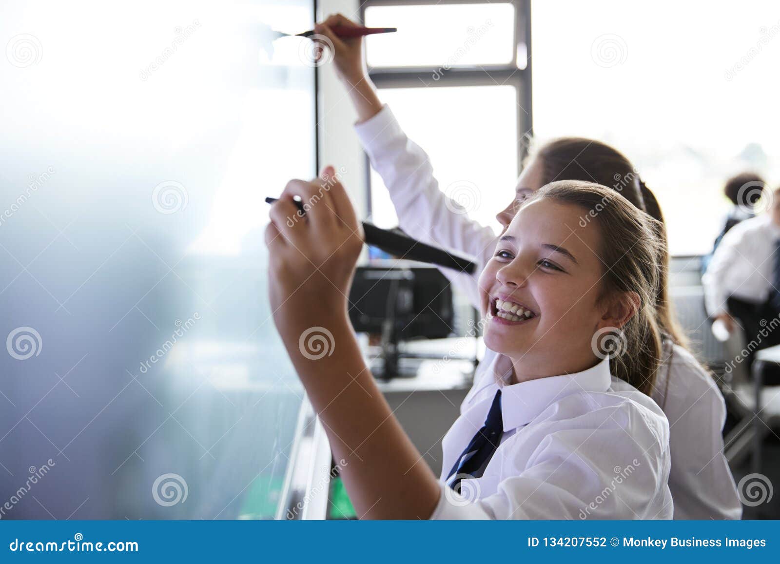 female high school students wearing uniform using interactive whiteboard during lesson